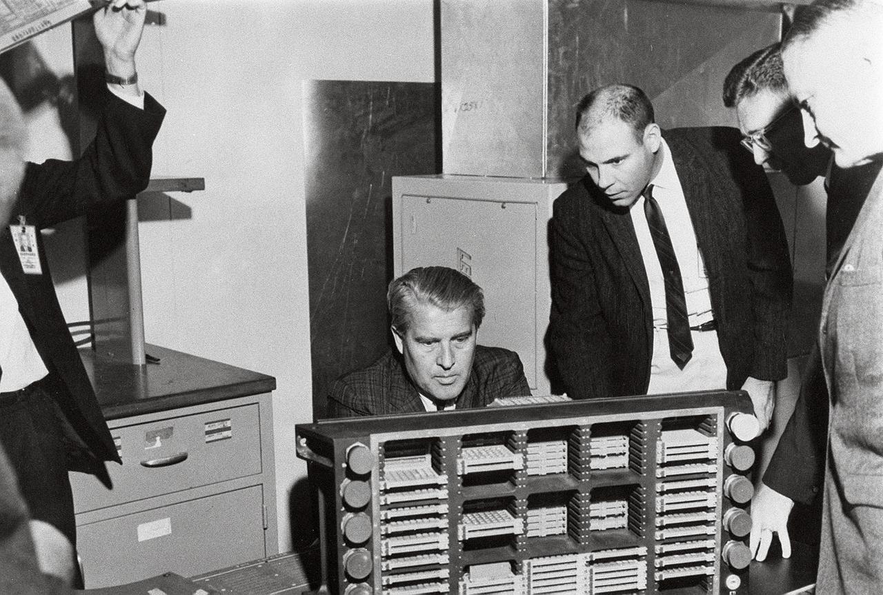 This photograph is dated March 10, 1966, and shows Dr. von Braun (seated) examining a Saturn computer in the Astrionics Laboratory at the Marshall Space Flight Center. Standing left to right are J.B. White, Brooks Moore, and Herman K. Weidner.