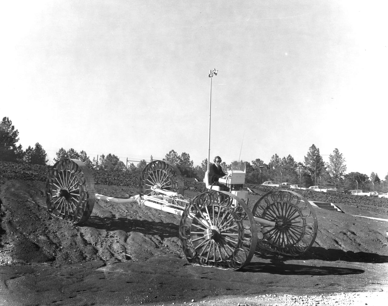 An engineer demonstrates a Mobility Test Article (MTA) at NASA’s Marshall Space Flight Center (MSFC) as he goes down a slope onto soft earth. This unit, weighing 1/6th as much as an actual vehicle, was built by the Bendix Corporation and was one of the concepts of a possible Lunar Roving Vehicle (LRV). The data provided by the MTA helped in designing the Lunar Roving Vehicle (LRV), developed under the direction of MSFC. The LRV was designed to allow Apollo astronauts a greater range of mobility during lunar exploration missions. 