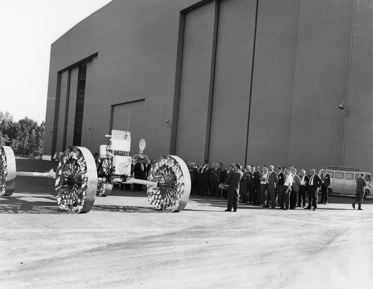 Newsmen listen as an engineer explains operations and capabilities of a Mobility Test Article (MTA) demonstrated at NASA’s Marshall Space Flight Center (MSFC). This unit, built by the Bendix Corporation, was one of the concepts of a possible Lunar Roving Vehicle (LRV). The data provided by the MTA helped in designing the LRV, developed under the direction of MSFC. The LRV was designed to allow Apollo astronauts a greater range of mobility during lunar exploration missions. 