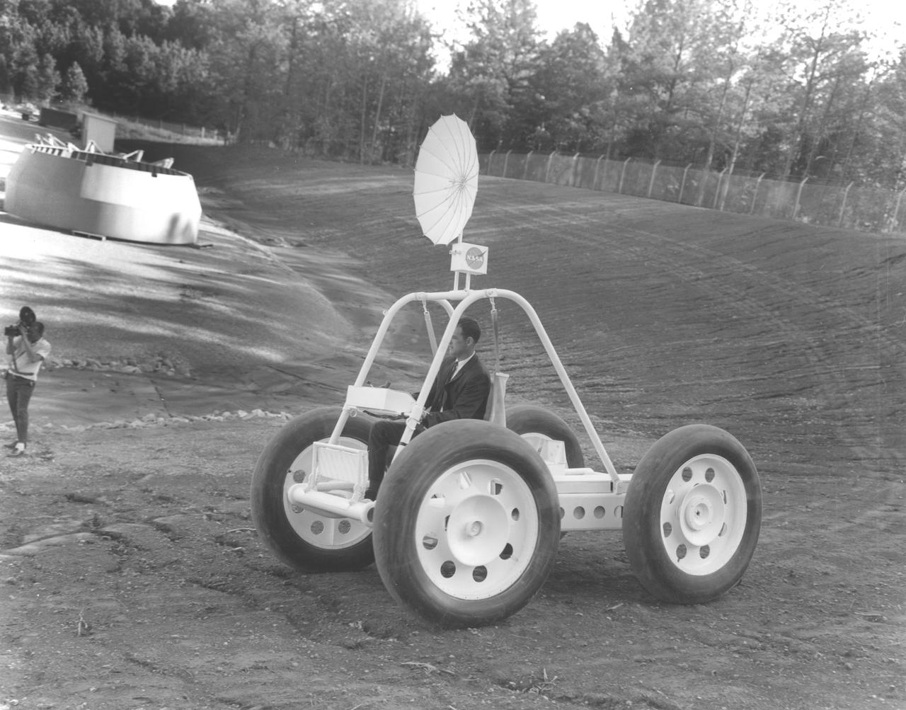 Built by Brown Engineering company of Huntsville, Alabama, a motorized mockup of a small Lunar Roving Vehicle (LRV) is being demonstrated at the Marshall Space Flight Center (MSFC).  This particular vehicle weighed about 1200 pounds and is almost 10 feet long, 7-feet and 2-inches wide, and 7-feet and 8-inches high. The LRV was developed under the direction of MSFC to provide astronauts with greater mobility on the lunar surface.