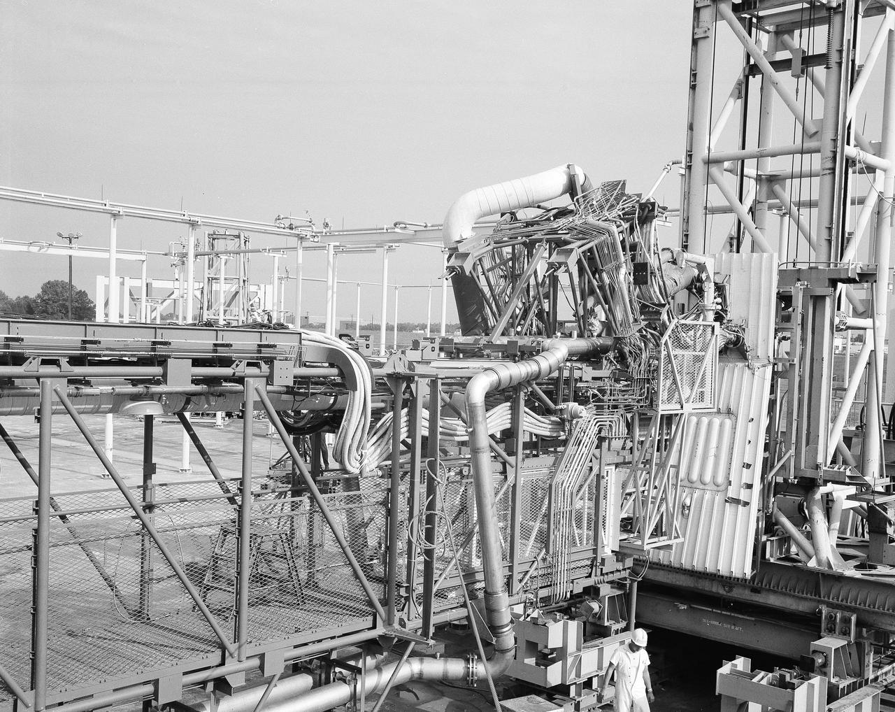 The Marshall Space Flight Center (MSFC) played a crucial role in the development of the huge Saturn rockets that delivered humans to the moon in the 1960s.  Many unique facilities existed at MSFC for the development and testing of the Saturn rockets.  Affectionately nicknamed “The Arm Farm”, the Random Motion/ Lift-Off Simulator was one of those unique facilities. This facility was developed to test the swingarm mechanisms that were used to hold the rocket in position until lift-off. The Arm Farm provided the capability of testing the detachment and reconnection of various arms under brutally realistic conditions.  The 18-acre facility consisted of more than a half dozen arm test positions and one position for testing access arms used by the Apollo astronauts. Each test position had two elements: a vehicle simulator for duplicating motions during countdown and launch; and a section duplicating the launch tower. The vehicle simulator duplicated the portion of the vehicle skin that contained the umbilical connections and personnel access hatches. Driven by a hydraulic servo system, the vehicle simulator produced relative motion between the vehicle and tower. On the Arm Farm, extreme environmental conditions (such as a launch scrub during an approaching Florida thunderstorm) could be simulated. The dramatic scenes that the Marshall engineers and technicians created at the Arm Farm permitted the gathering of crucial technical and engineering data to ensure a successful real time launch from the Kennedy Space Center. 