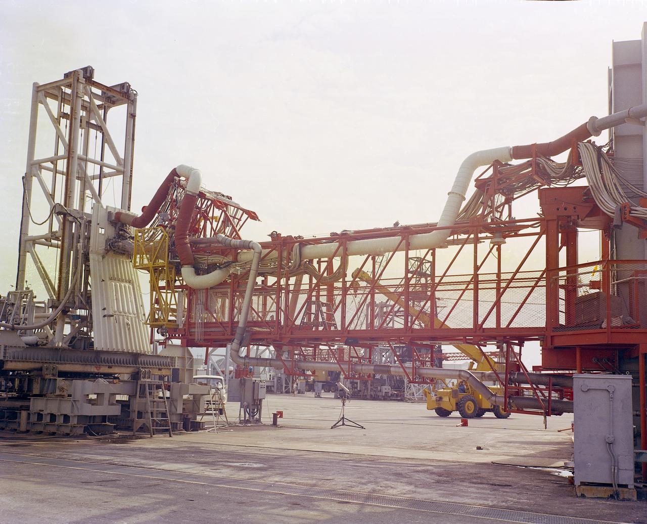 The Marshall Space Flight Center (MSFC) played a crucial role in the development of the huge Saturn rockets that delivered humans to the moon in the 1960s.  Many unique facilities existed at MSFC for the development and testing of the Saturn rockets. Affectionately nicknamed “The Arm Farm”, the Random Motion/ Lift-Off Simulator was one of those unique facilities. This facility was developed to test the swingarm mechanisms that were used to hold the rocket in position until lift-off. The Arm Farm provided the capability of testing the detachment and reconnection of various arms under brutally realistic conditions.  The 18-acre facility consisted of more than a half dozen arm test positions and one position for testing access arms used by the Apollo astronauts. Each test position had two elements: a vehicle simulator for duplicating motions during countdown and launch; and a section duplicating the launch tower. The vehicle simulator duplicated the portion of the vehicle skin that contained the umbilical connections and personnel access hatches. Driven by a hydraulic servo system, the vehicle simulator produced relative motion between the vehicle and tower. On the Arm Farm, extreme environmental conditions (such as a launch scrub during an approaching Florida thunderstorm) could be simulated. The dramatic scenes that the Marshall engineers and technicians created at the Arm Farm permitted the gathering of crucial technical and engineering data to ensure a successful real time launch from the Kennedy Space Center. 