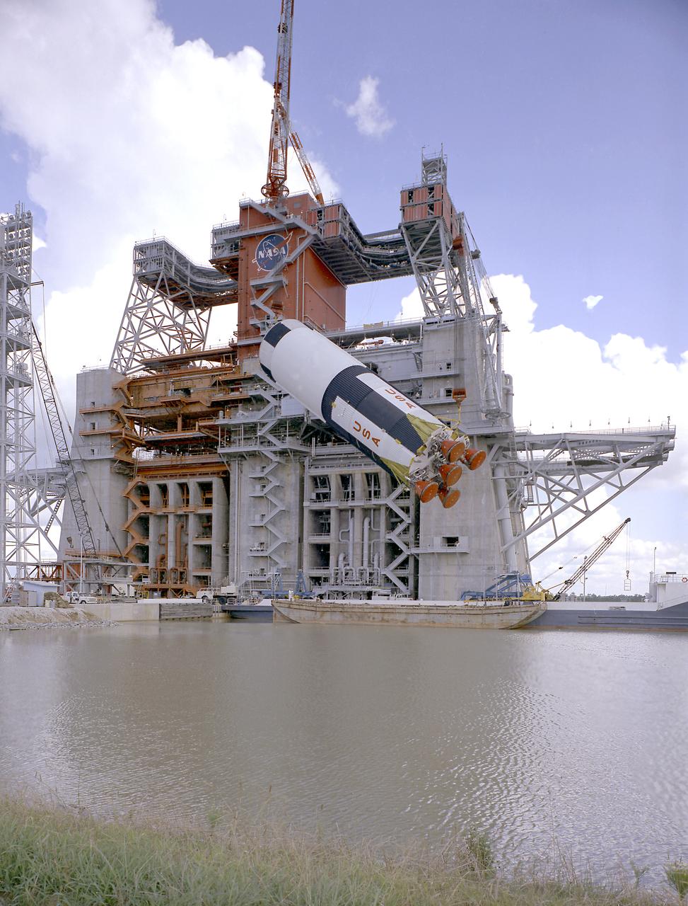 This photograph is a view of the Saturn V S-IC-5 (first) flight stage being hoisted into the S-IC-B1 test stand at the Mississippi Test Facility (MTF), Bay St. Louis, Mississippi. Begirning operations in 1966, the MTF has two test stands, a dual-position structure for running the S-IC stage at full throttle, and two separate stands for the S-II (Saturn V third) stage. It became the focus of the static test firing program. The completed S-IC stage was shipped from Michoud Assembly Facility (MAF) to the MTF. The stage was then installed into the 124-meter-high test stand for static firing tests before shipment to the Kennedy Space Center for final assembly of the Saturn V vehicle. The MTF was renamed to the National Space Technology Laboratory (NSTL) in 1974 and later to the Stennis Space Center (SSC) in May 1988. 
