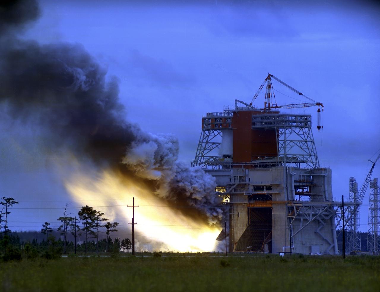 This photograph is a view of the Saturn V S-IC-5 (first) flight stage static test firing at the S-IC-B1 test stand at the Mississippi Test Facility (MTF), Bay St. Louis, Mississippi. Begirning operations in 1966, the MTF has two test stands, a dual-position structure for running the S-IC stage at full throttle, and two separate stands for the S-II (Saturn V third) stage. It became the focus of the static test firing program. The completed S-IC stage was shipped from Michoud Assembly Facility (MAF) to the MTF. The stage was then installed into the 407-foot-high test stand for the static firing tests before shipment to the Kennedy Space Center for final assembly of the Saturn V vehicle. The MTF was renamed to the National Space Technology Laboratory (NSTL) in 1974 and later to the Stennis Space Center (SSC) in May 1988. 