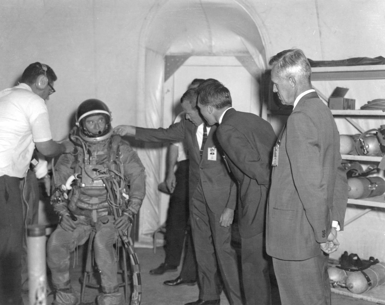Astronaut L. Gordon Cooper checks the neck ring of a space suit worn by Marshall Space Flight Center (MSFC) Director, Dr. von Braun before he submerges into the water of the MSFC Neutral Buoyancy Simulator (NBS). Wearing a pressurized suit and weighted to a neutrally buoyant condition, Dr. von Braun was able to perform tasks underwater which simulated weightless conditions found in space.