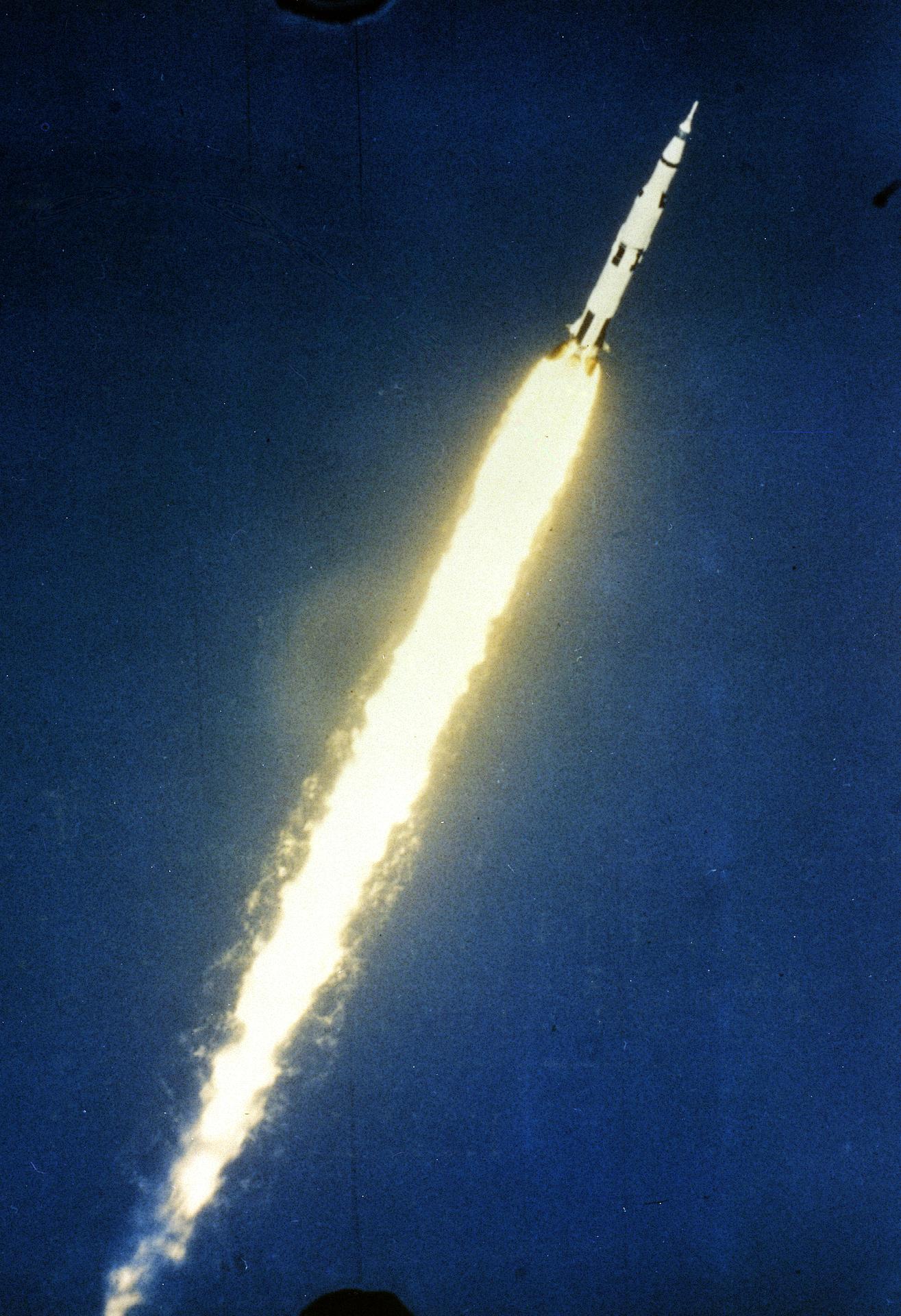 The Saturn V rocket trails a plume of flame as it launches into space