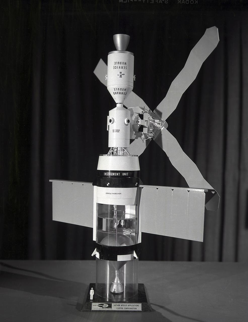 This photograph is of a model of the Skylab with the Command/Service Module being docked. In an early effort to extend the use of Apollo for further applications, NASA established the Apollo Applications Program (AAP) in August of 1965. The AAP was to include long duration Earth orbital missions during which astronauts would carry out scientific, technological, and engineering experiments in space by utilizing modified Saturn launch vehicles and the Apollo spacecraft. Established in 1970, the Skylab Program was the forerurner of the AAP. The goals of the Skylab were to enrich our scientific knowledge of the Earth, the Sun, the stars, and cosmic space; to study the effects of weightlessness on living organisms, including man; to study the effects of the processing and manufacturing of materials utilizing the absence of gravity; and to conduct Earth resource observations. The Skylab also conducted 19 selected experiments submitted by high school students. Skylab's 3 different 3-man crews spent up to 84 days in Earth orbit. The Marshall Space Flight Center (MSFC) had responsibility for developing and integrating most of the major components of the Skylab: the Orbital Workshop (OWS), Airlock Module (AM), Multiple Docking Adapter (MDA), Apollo Telescope Mount (ATM), Payload Shroud (PS), and most of the experiments. MSFC was also responsible for providing the Saturn IB launch vehicles for three Apollo spacecraft and crews and a Saturn V launch vehicle for the Skylab.