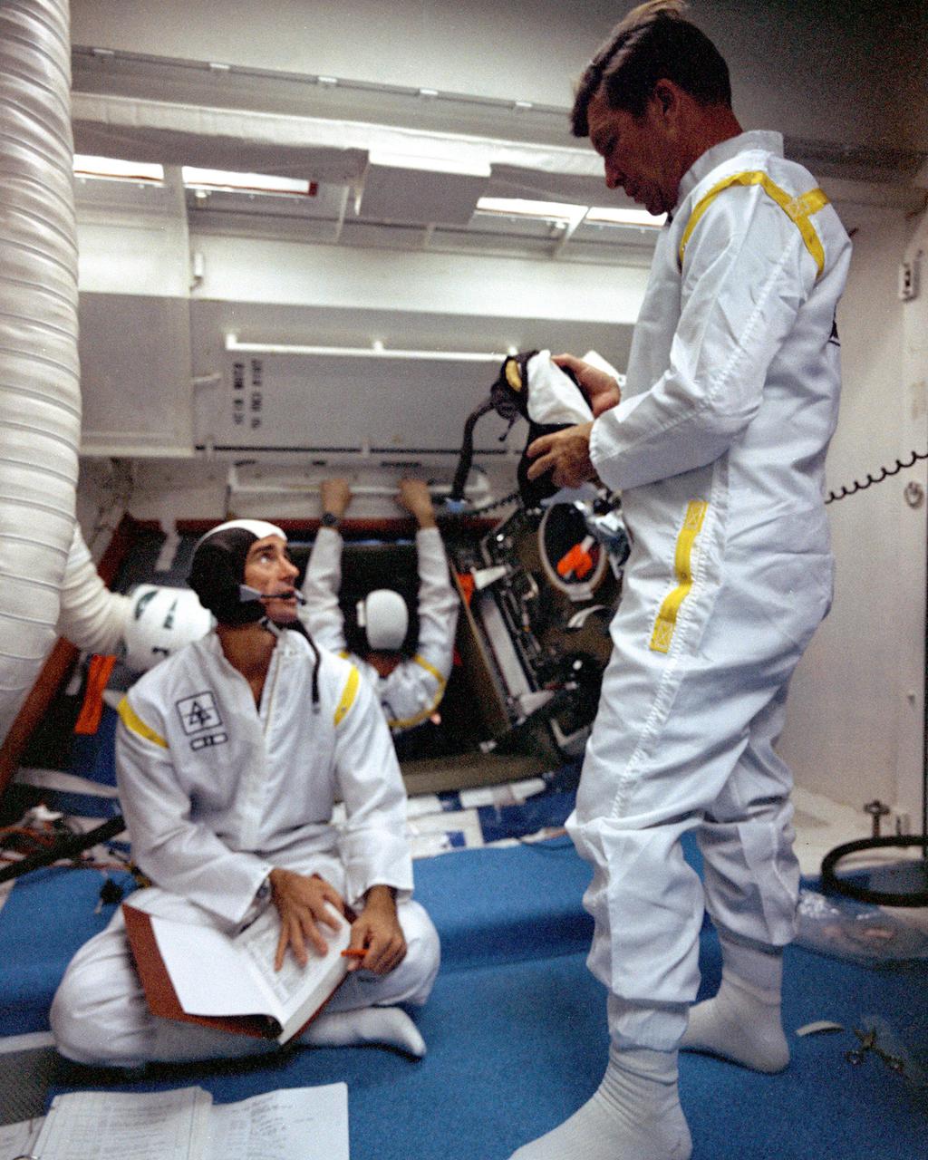 KENNEDY SPACE CENTER, FLA. - Apollo 7 Command Module Pilot Donn F. Eisele enters the spacecraft at Pad 34 while fellow crew members, Commander Walter M. Schirra Jr., left, and Lunar Module Pilot Walter Cunningham hold a brief discussion before they repeat that portion of the Plugs-Out test at the pad.  The tests are being conducted in preparation for the scheduled launch of Apollo 7, the first manned lunar orbital mission.