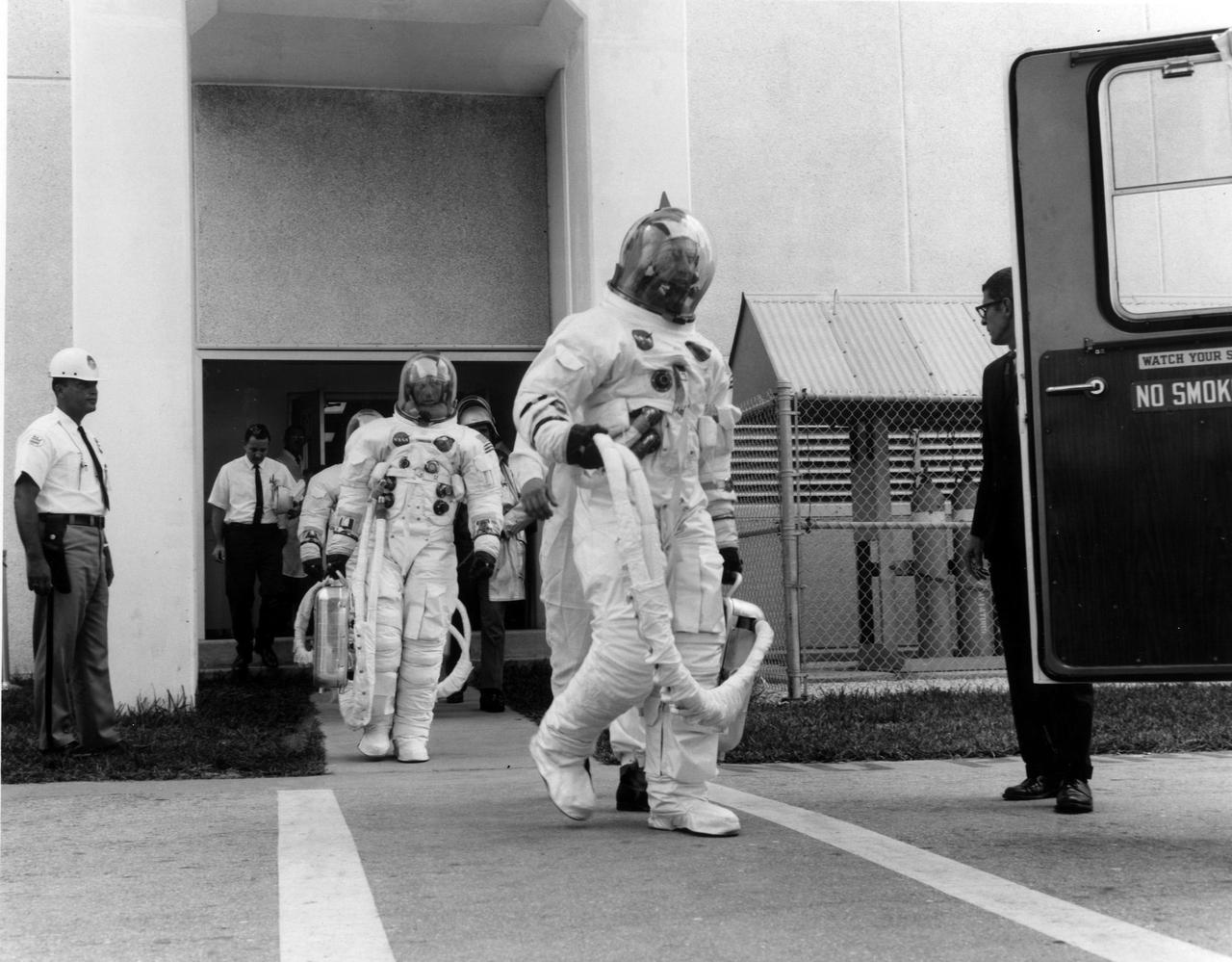 KENNEDY SPACE CENTER, FLA. -- Apollo 7 prime crew members, front to back, Donn F. Eisele, Walter M. Schirra Jr. and Walter Cunningham, leave the Kennedy Space Center's Manned Spacecraft Operations Building for a 20-minute ride in a transfer van to Cape Kennedy's Launch Complex 34, where they participated in a Space Vehicle Emergency Egress Test. The trio will pilot the National Aeronautics and Space Administration's first manned Apollo mission.