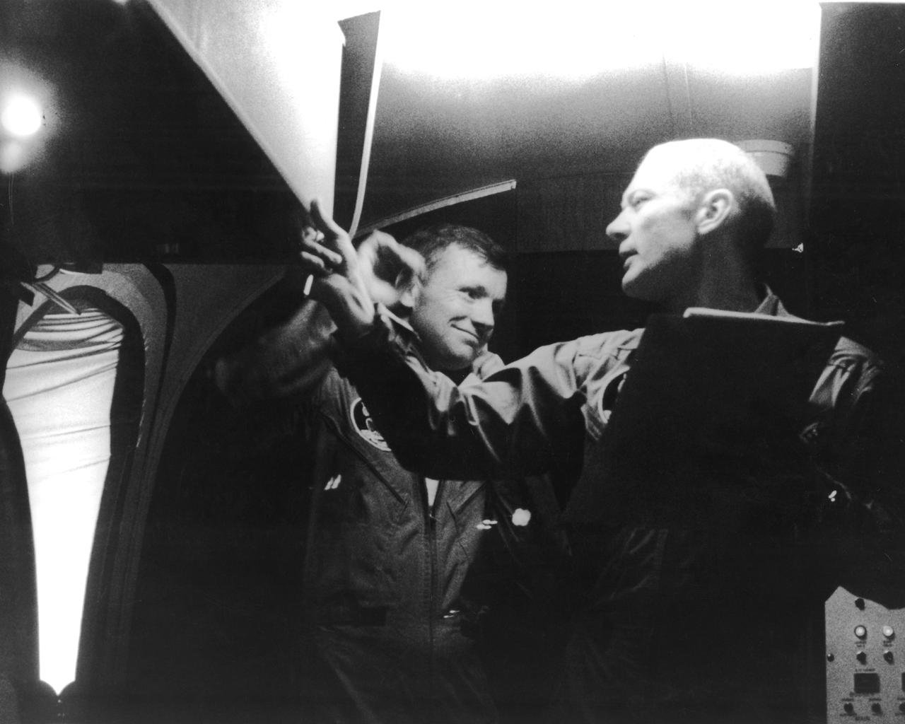 The Apollo 11 mission, the first manned lunar mission, launched aboard the Saturn V launch vehicle from the Kennedy Space Center, Florida on July 16, 1969 and safely returned to Earth on July 24, 1969. Aboard were astronauts Neil A. Armstrong, commander; Michael Collins, Command Module (CM) pilot; and Edwin E. Aldrin Jr., Lunar Module (LM) pilot. The CM, piloted by Michael Collins, remained in a parking orbit around the Moon while the LM, named “Eagle’’, carrying astronauts Neil Armstrong and Edwin Aldrin, landed on the Moon. Armstrong was the first human to ever stand on the lunar surface, followed by Edwin (Buzz) Aldrin. The surface exploration was concluded in 2½ hours. Once the crew collected 47 pounds of lunar surface material for analysis back on Earth, the LM redocked with the CM for the crew’s return to Earth. Following splash down in the Pacific Ocean, Navy para-rescue men recovered the capsule housing the 3-man crew. The crew was airlifted to safety aboard the U.S.S. Hornet, where they were quartered in a Mobile Quarantine Facility (MQF). Astronaut Collins took this snapshot of astronauts Armstrong (center) and Aldrin inside of the MQF.