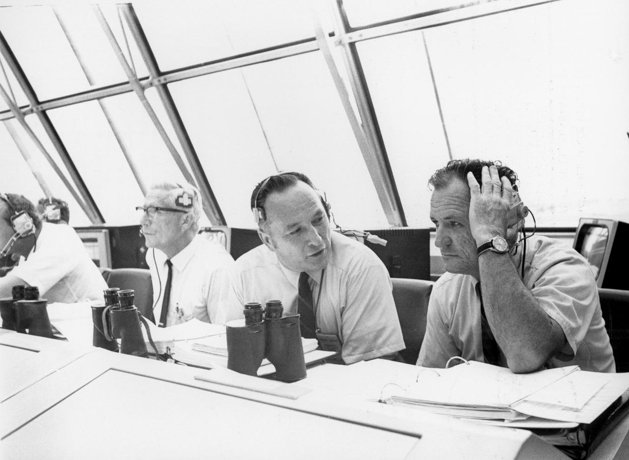 Lee B. James (left), manager of the Saturn Program at the Marshall Space flight Center (MSFC), talks with Isom Pigell in the firing room 1 of the Kennedy Space Center (KSC) control center during the countdown demonstration test for the Apollo 11 mission. At left is Dr. Hans C. Gruen of KSC. The Apollo 11 mission, the first lunar landing mission, launched from the KSC in Florida via the MSFC developed Saturn V launch vehicle on July 16, 1969 and safely returned to Earth on July 24, 1969. Aboard the space craft were astronauts Neil A. Armstrong, commander; Michael Collins, Command Module (CM) pilot; and Edwin E. (Buzz) Aldrin Jr., Lunar Module (LM) pilot. The CM, “Columbia”, piloted by Collins, remained in a parking orbit around the Moon while the LM, “Eagle’’, carrying astronauts Armstrong and Aldrin, landed on the Moon. On July 20, 1969, Armstrong was the first human to ever stand on the lunar surface, followed  by Aldrin. During 2½ hours of surface exploration, the crew collected 47 pounds of lunar surface material for analysis back on Earth. With the success of Apollo 11, the national objective to land men on the Moon and return them safely to Earth had been accomplished. 