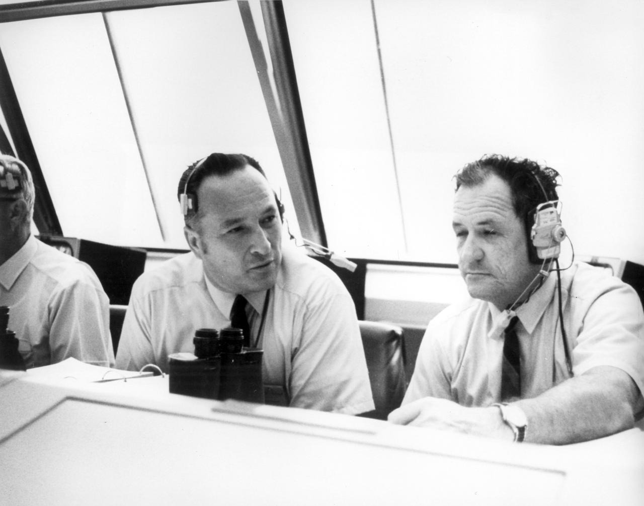 Lee B. James (left), manager of the Saturn Program at the Marshall Space flight Center (MSFC), talks with Isom Pigell in the firing room 1 of the Kennedy Space Center (KSC) control center during the countdown demonstration test for the Apollo 11 mission. The Apollo 11 mission, the first lunar landing mission, launched from the KSC in Florida via the MSFC developed Saturn V launch vehicle on July 16, 1969 and safely returned to Earth on July 24, 1969. Aboard the space craft were astronauts Neil A. Armstrong, commander; Michael Collins, Command Module (CM) pilot; and Edwin E. (Buzz) Aldrin Jr., Lunar Module (LM) pilot. The CM, “Columbia”, piloted by Collins, remained in a parking orbit around the Moon while the LM, “Eagle’’, carrying astronauts Armstrong and Aldrin, landed on the Moon. On July 20, 1969, Armstrong was the first human to ever stand on the lunar surface, followed by Aldrin. During 2½ hours of surface exploration, the crew collected 47 pounds of lunar surface material for analysis back on Earth. With the success of Apollo 11, the national objective to land men on the Moon and return them safely to Earth had been accomplished.