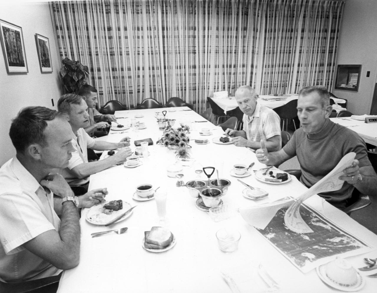 Chief astronaut and director of flight crew operations, Donald K. Slayton (right front) reviews lunar charts with Apollo 11 astronauts Michael Collins (left), Neil Armstrong, and Edwin Aldrin (next to Slayton) during breakfast a short time before the three men launched for the first Moon landing mission. Sharing breakfast with the crew was William Anders (left rear), Lunar Module pilot for the Apollo 8 lunar orbit mission. The Apollo 11 mission launched from the NASA Kennedy Space Center (KSC) in Florida via the Marshall Space Flight Center (MSFC) developed Saturn V launch vehicle on July 16, 1969 and safely returned to Earth on July 24, 1969. The CM, “Columbia”, piloted by Collins, remained in a parking orbit around the Moon while the LM, “Eagle’’, carrying astronauts Armstrong and Aldrin, landed on the Moon. On July 20, 1969, Armstrong was the first human to ever stand on the lunar surface, followed by Aldrin. During 2½ hours of surface exploration, the crew collected 47 pounds of lunar surface material for analysis back on Earth. With the success of Apollo 11, the national objective to land men on the Moon and return them safely to Earth had been accomplished.  