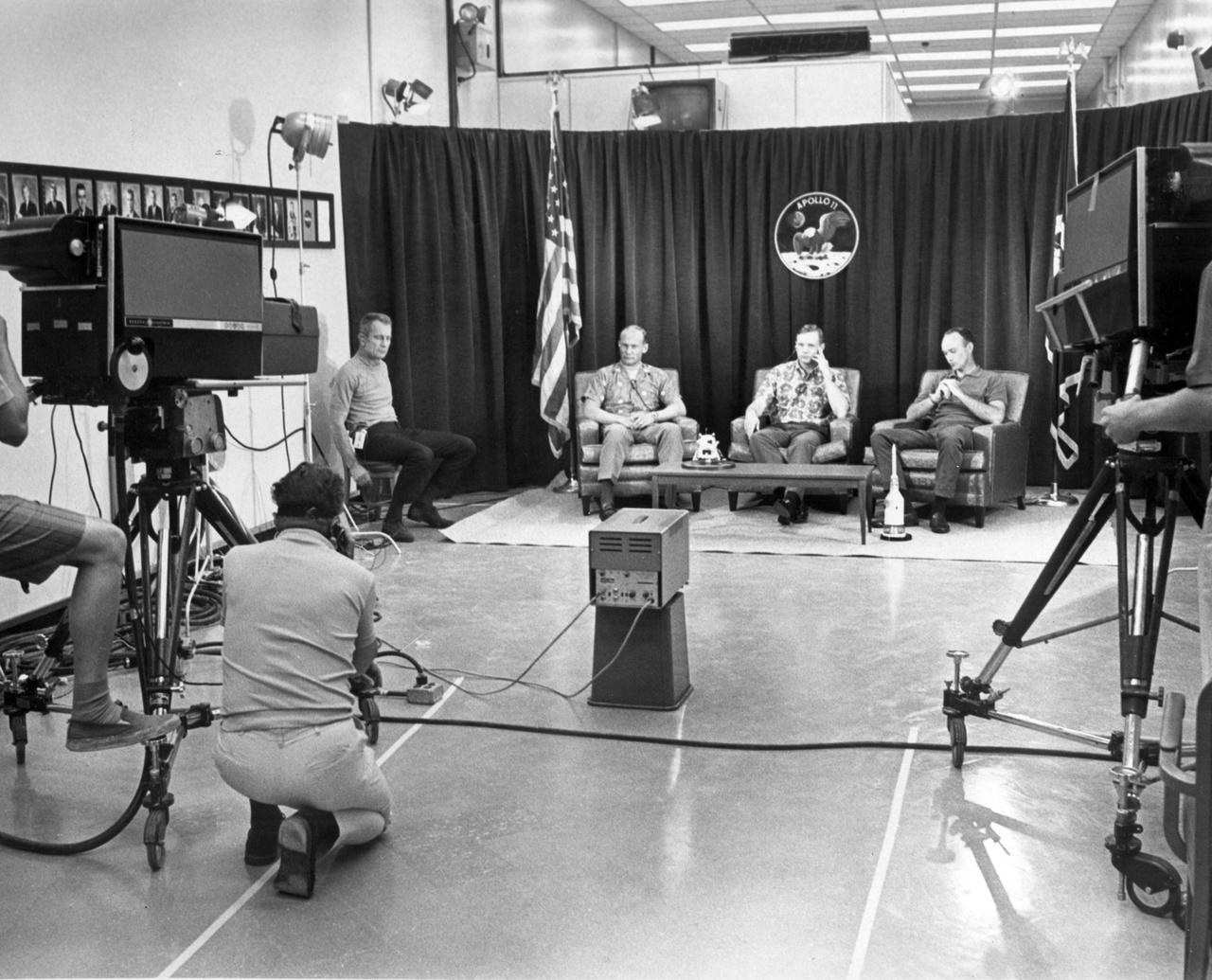The night before launch day, Apollo 11 crew members (R-L) Michael Collins, Neil Armstrong, and Edwin Aldrin, participated in a closed circuit press conference the night before they began their historic lunar landing mission. At far left is chief astronaut and director of flight crew operations, Donald K. Slayton.  The press conference with questions via intercom, was held under semi-isolation conditions to avoid exposing the astronauts to possible illness at the last minute. The Apollo 11 mission, the first lunar landing mission, launched from the Kennedy Space Center (KSC) in Florida via the Marshall Space Flight Center (MSFC) developed Saturn V launch vehicle on July 16, 1969 and safely returned to Earth on July 24, 1969. Aboard the space craft were astronauts Neil A. Armstrong, commander; Michael Collins, Command Module (CM) pilot; and Edwin E. (Buzz) Aldrin Jr., Lunar Module (LM) pilot. The CM, “Columbia”, piloted by Collins, remained in a parking orbit around the Moon while the LM, “Eagle’’, carrying astronauts Armstrong and Aldrin, landed on the Moon. On July 20, 1969, Armstrong was the first human to ever stand on the lunar surface, followed by Aldrin. During 2½ hours of surface exploration, the crew collected 47 pounds of lunar surface material for analysis back on Earth. With the success of Apollo 11, the national objective to land men on the Moon and return them safely to Earth had been accomplished.  