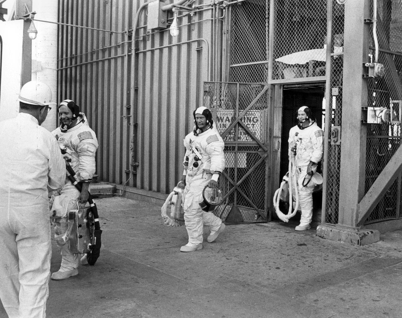 Apollo 11 crew members (left to right) Neil Armstrong, Edwin Aldrin, and Michael Collins, wearing space suits, leave the elevator after descending from the top of the launch tower.  The three had just completed participation in the countdown demonstration test for the upcoming Apollo 11 mission. The Apollo 11 mission, the first lunar landing mission, launched from the Kennedy Space Center (KSC) in Florida via the Marshall Space Flight Center (MSFC) developed Saturn V launch vehicle on July 16, 1969 and safely returned to Earth on July 24, 1969. Aboard the space craft were astronauts Neil A. Armstrong, commander; Michael Collins, Command Module (CM) pilot; and Edwin E. (Buzz) Aldrin Jr., Lunar Module (LM) pilot. The CM, “Columbia”, piloted by Collins, remained in a parking orbit around the Moon while the LM, “Eagle’’, carrying astronauts Armstrong and Aldrin, landed on the Moon. On July 20, 1969, Armstrong was the first human to ever stand on the lunar surface, followed by Aldrin. During 2½ hours of surface exploration, the crew collected 47 pounds of lunar surface material for analysis back on Earth. With the success of Apollo 11, the national objective to land men on the Moon and return them safely to Earth had been accomplished.  