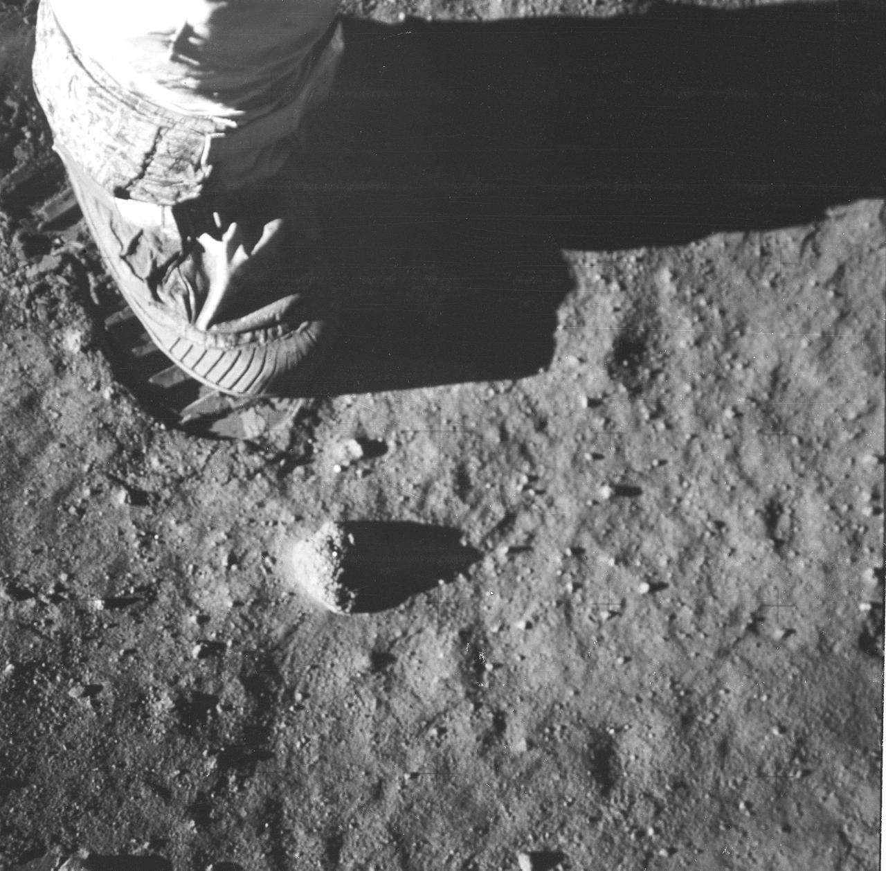 This is a close-up view of an astronaut’s foot and footprint in the lunar soil, photographed by a 70 mm lunar surface camera during the Apollo 11 lunar surface extravehicular activity (EVA). The first manned lunar mission launched via a Saturn V launch vehicle from the Kennedy Space Center, Florida on July 16, 1969 and safely returned to Earth on July 24, 1969. The Saturn V vehicle was developed by the Marshall Space Flight Center (MSFC) under the direction of Dr. Wernher von Braun. The 3-man crew aboard the flight consisted of astronauts Neil A. Armstrong, mission commander; Edwin E. Aldrin, Jr., Lunar Module (LM) Pilot; and Michael Collins, Command Module (CM) pilot. The LM landed on the moon’s surface on July 20, 1969 in the region known as Mare Tranquilitatis (the Sea of Tranquility).  Armstrong was the first human to ever stand on the lunar surface. As he stepped off the LM, Armstrong proclaimed, “That’s one small step for man, one giant leap for mankind”. He was followed by Edwin (Buzz) Aldrin, describing the lunar surface as magnificent desolation. Astronaut Collins piloted the CM in a parking orbit around the Moon. During a 2½ hour surface exploration, the crew collected 47 pounds of lunar surface material which was returned to Earth for analysis. With the success of Apollo 11, the national objective to land men on the Moon and return them safely to Earth had been accomplished. 