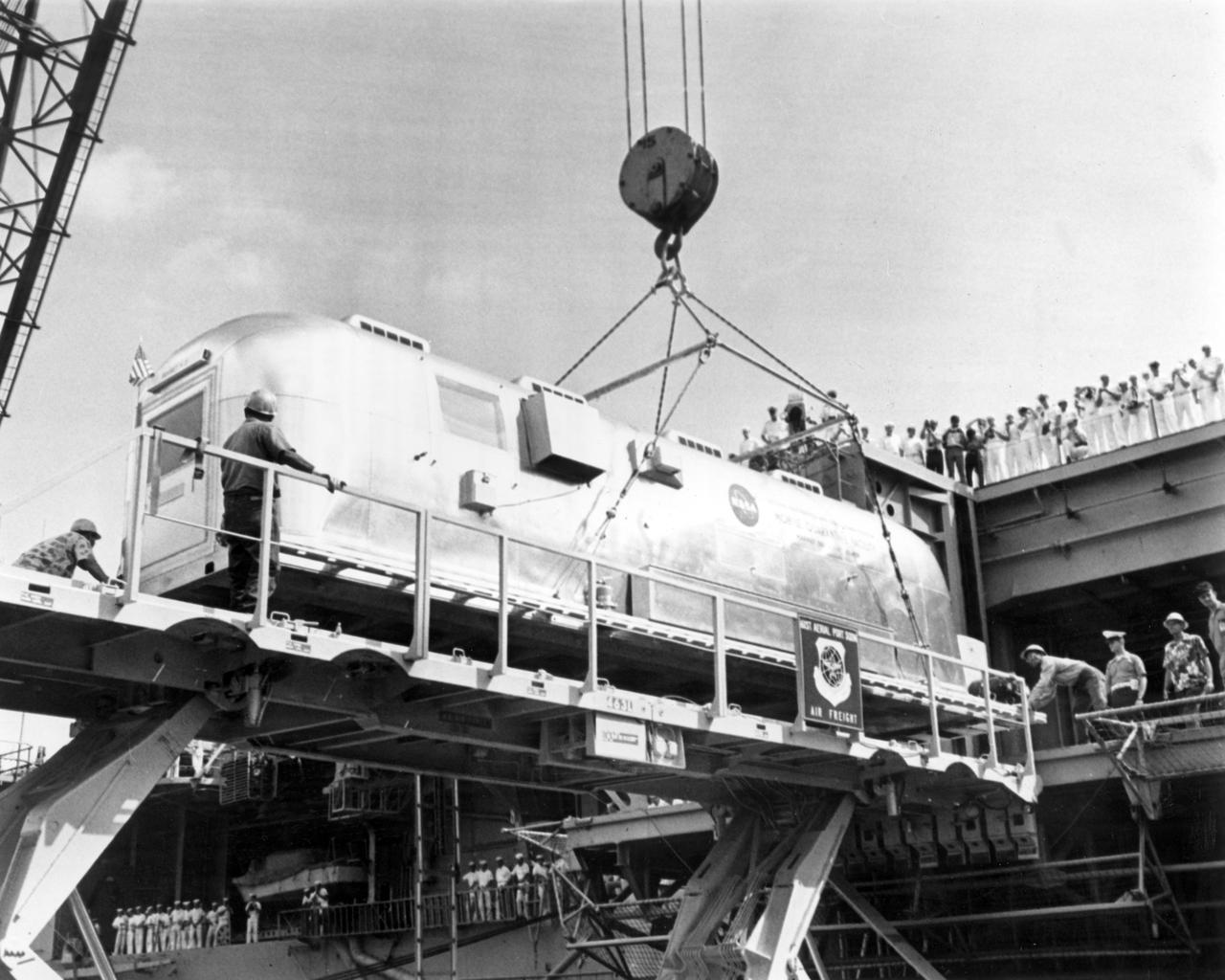 The Apollo 11 mission, the first manned lunar mission, launched from the Kennedy Space Center, Florida via the Marshall Space Flight Center (MSFC) developed Saturn V launch vehicle on July 16, 1969 and safely returned to Earth on July 24, 1969. Aboard the space craft were astronauts Neil A. Armstrong, commander; Michael Collins, Command Module (CM) pilot; and Edwin E. Aldrin Jr., Lunar Module (LM) pilot. The CM, piloted by Michael Collins remained in a parking orbit around the Moon while the LM, named “Eagle’’, carrying astronauts Neil Armstrong and Edwin Aldrin, landed on the Moon. During 2½ hours of surface exploration, the crew collected 47 pounds of lunar surface material for analysis back on Earth. The recovery operation took place in the Pacific Ocean where Navy para-rescue men recovered the capsule housing the 3-man Apollo 11 crew. The crew was airlifted to safety aboard the U.S.S. Hornet recovery ship, where they were quartered in a Mobile Quarantine Facility (MQF) which served as their home for 21 days. In this photo taken at Pearl Harbor, Hawaii, the quarantined housing facility is being lowered from the U.S.S. Hornet, onto a trailer for transport to Hickam Field. From there, it was loaded aboard an Air Force C-141 jet and flown back to Ellington Air Force Base Texas, and then on to the NASA Manned Spacecraft Center (MSC) Lunar Receiving Laboratory in Houston, Texas.