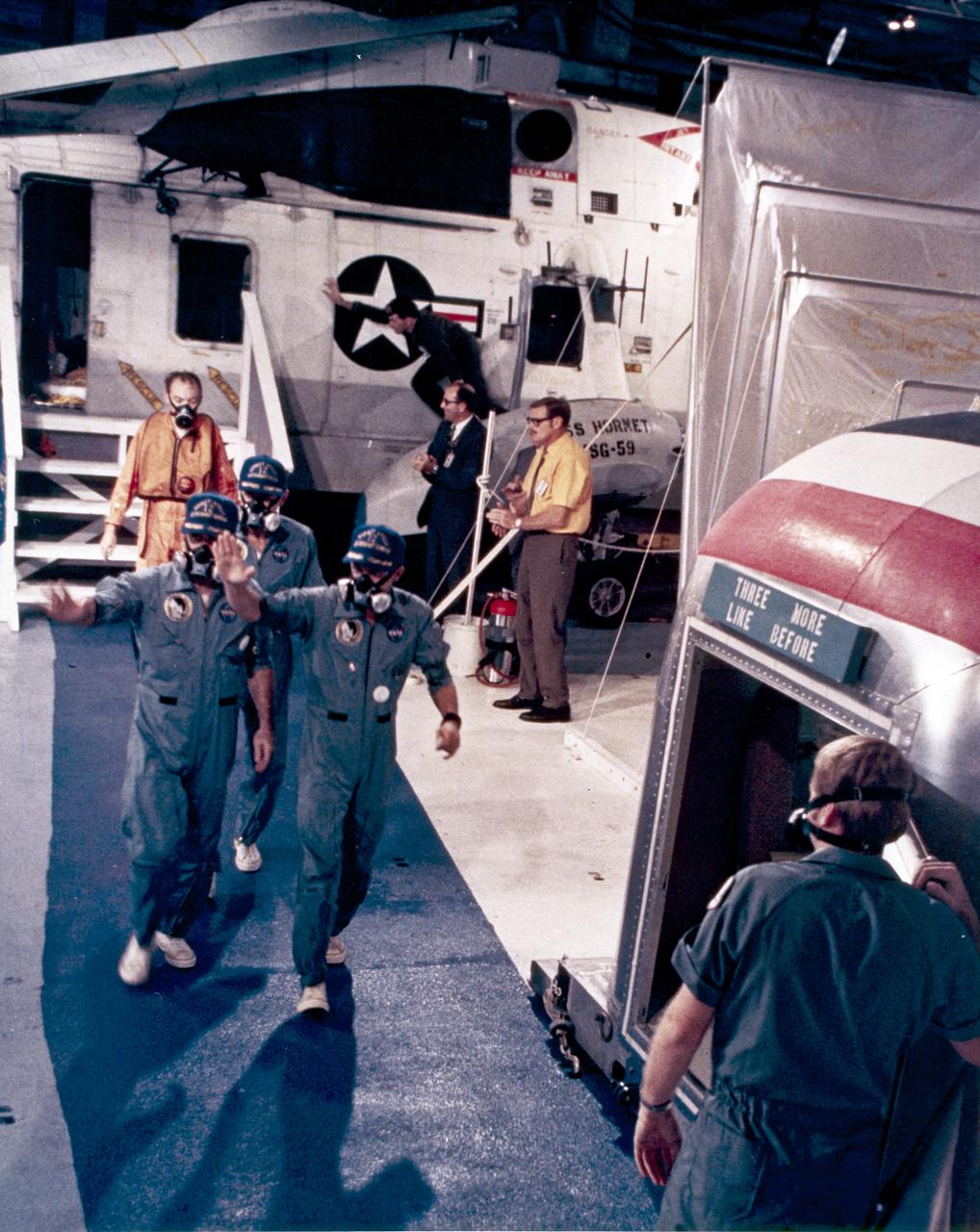 Aboard the recovery ship, USS Hornet, Apollo 12 astronauts wave to the crowd as they enter the mobile quarantine facility. The recovery operation took place in the Pacific Ocean after the splashdown of the Command Module capsule. Navy para-rescue men recovered the capsule housing the 3-man Apollo 12 crew. The second manned lunar landing mission, Apollo 12 launched from launch pad 39-A at Kennedy Space Center in Florida on November 14, 1969 via a Saturn V launch vehicle. The Saturn V was developed by the Marshall Space Flight Center (MSFC) under the direction of Dr. Wernher von Braun. Aboard Apollo 12 was a crew of three astronauts: Alan L. Bean, pilot of the Lunar Module (LM), Intrepid; Richard Gordon, pilot of the Command Module (CM), Yankee Clipper; and Spacecraft Commander Charles Conrad. The LM, Intrepid, landed astronauts Conrad and Bean on the lunar surface in what’s known as the Ocean of Storms while astronaut Richard Gordon piloted the CM, Yankee Clipper, in a parking orbit around the Moon. Lunar soil activities included the deployment of the Apollo Lunar Surface Experiments Package (ALSEP), finding the unmanned Surveyor 3 that landed on the Moon on April 19, 1967, and collecting 75 pounds (34 kilograms) of rock samples.  Apollo 12 safely returned to Earth on November 24, 1969.