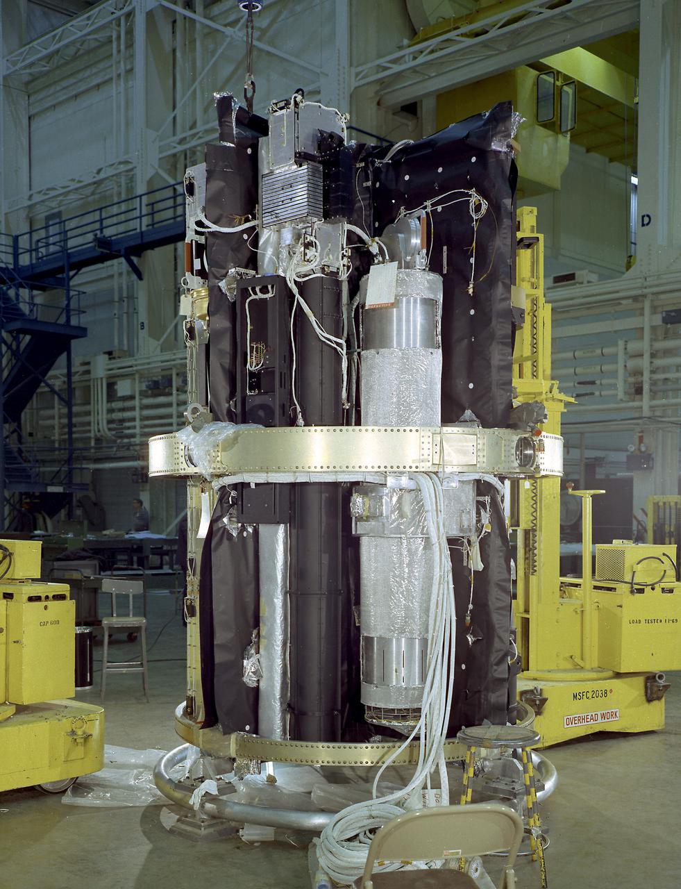 The Apollo Telescope Mount (ATM), designed and developed by the Marshall Space Flight Center, served as the primary scientific instrument unit aboard the Skylab. The ATM contained eight complex astronomical instruments designed to observe the Sun over a wide spectrum from visible light to x-rays. This image shows the ATM spar assembly. All solar telescopes, the fine Sun sensors, and some auxiliary systems are mounted on the spar, a cruciform lightweight perforated metal mounting panel that divides the 10-foot long canister lengthwise into four equal compartments. The spar assembly was nested inside a cylindrical canister that fit into the rack, a complex frame, and was protected by the solar shield.
