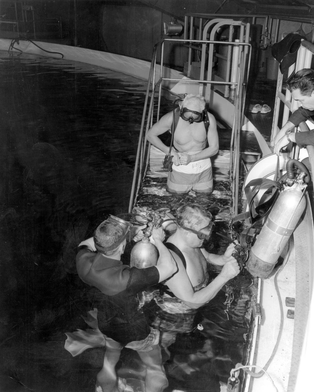 Marshall Space Flight Center’s (MSFC) Dr. Ernst Stuhlinger, Director of Research Projects Office; and Dr. Wernher von Braun, center director, along with others, took a swim in the Neutral Buoyancy Simulator (NBS) at MSFC. A safety diver adjusts scuba equipment worn by von Braun, while Stuhlinger adjusts his weight belt prior to entering the tank. In the NBS, subjects were weighted to a neutrally buoyant condition underwater to perform and practice tasks in a simulated weightless condition as would be encountered in space.