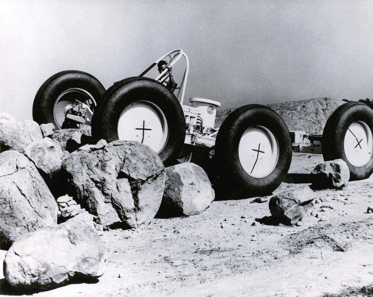 A test engineer drove a Mobility Test Article (MTA) of a possible future Lunar Roving Vehicle (LRV) over rocks during tests in Arizona.  The machine was built by General Motors for NASA’s Marshall Space Flight Center (MSFC). Under the direction of MSFC, the LRV was designed to allow Apollo astronauts a greater range of mobility during lunar exploration missions.