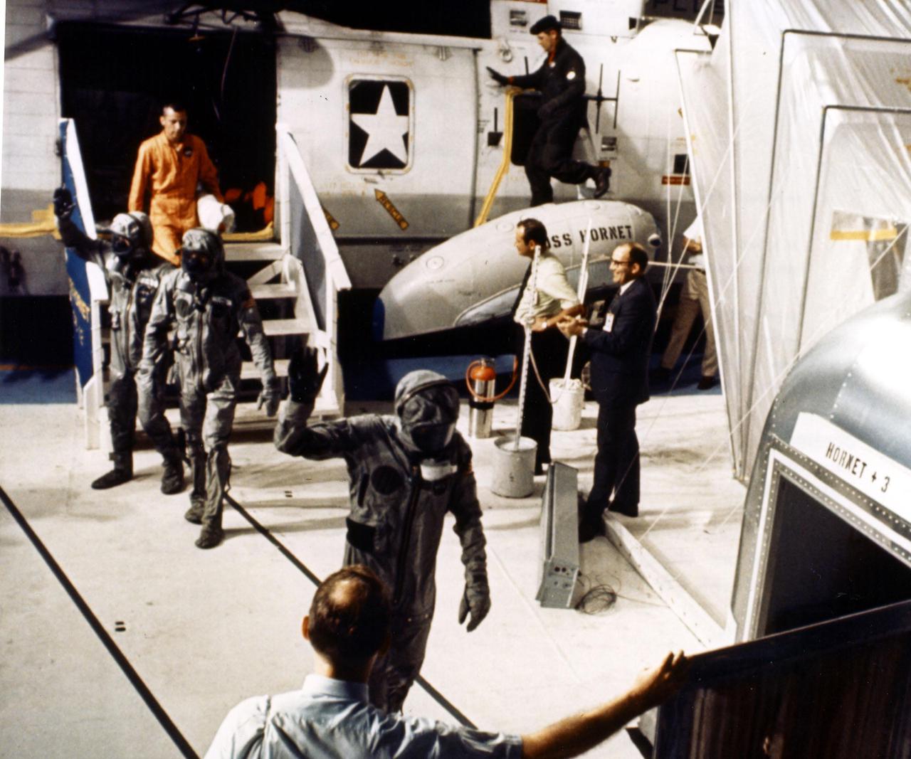 JOHNSON SPACE CENTER, HOUSTON, TEXAS  - A technician aboard the USS Hornet holds the Mobile Quarantine Facility door open for the Apollo 11 astronauts as they leave the recovery helicopter.  Astronauts, left to right, Edwin E. Aldrin Jr., Neil A. Armstrong and Michael Collins were taken to the USS Hornet after their Lunar Landing mission came to a successful completion at 12:50 p.m. EDT.