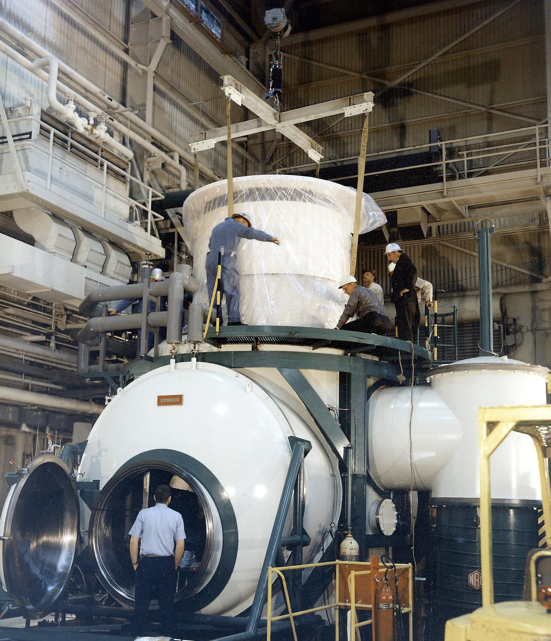 The Apollo Telescope Mount (ATM) was designed and developed by the Marshall Space Flight Center (MSFC) and served as the primary scientific instrument unit aboard Skylab (1973-1979). The ATM consisted of eight scientific instruments as well as a number of smaller experiments. In this image, the thermal unit, that controlled the temperature stability of the ATM, is being installed into a vacuum chamber. 