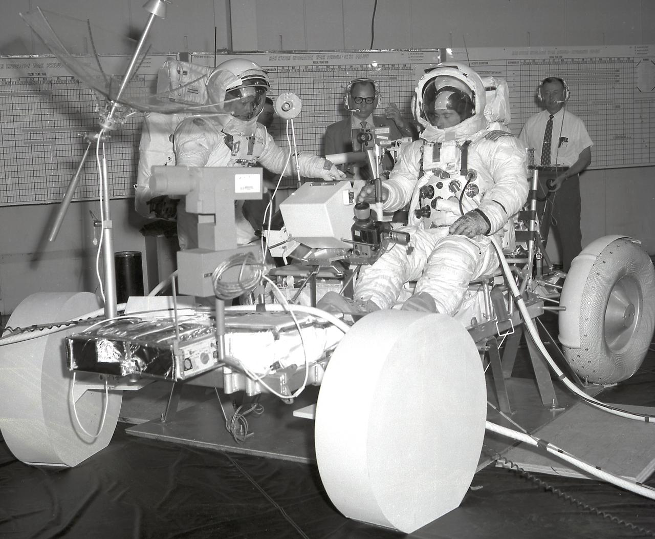 This image depicts the Apollo 16 mission astronauts John Young (right) and Charles Duke (left) in pressure suits during a final crew training on the Lunar Roving Vehicle (LRV) at the Marshall Space Flight Center (MSFC), building 4619. Developed by the MSFC, the LRV was the lightweight electric car designed to increase the range of mobility and productivity of astronauts on the lunar surface. It was used on the last three Apollo missions; Apollo 15, Apollo 16, and Apollo 17. 