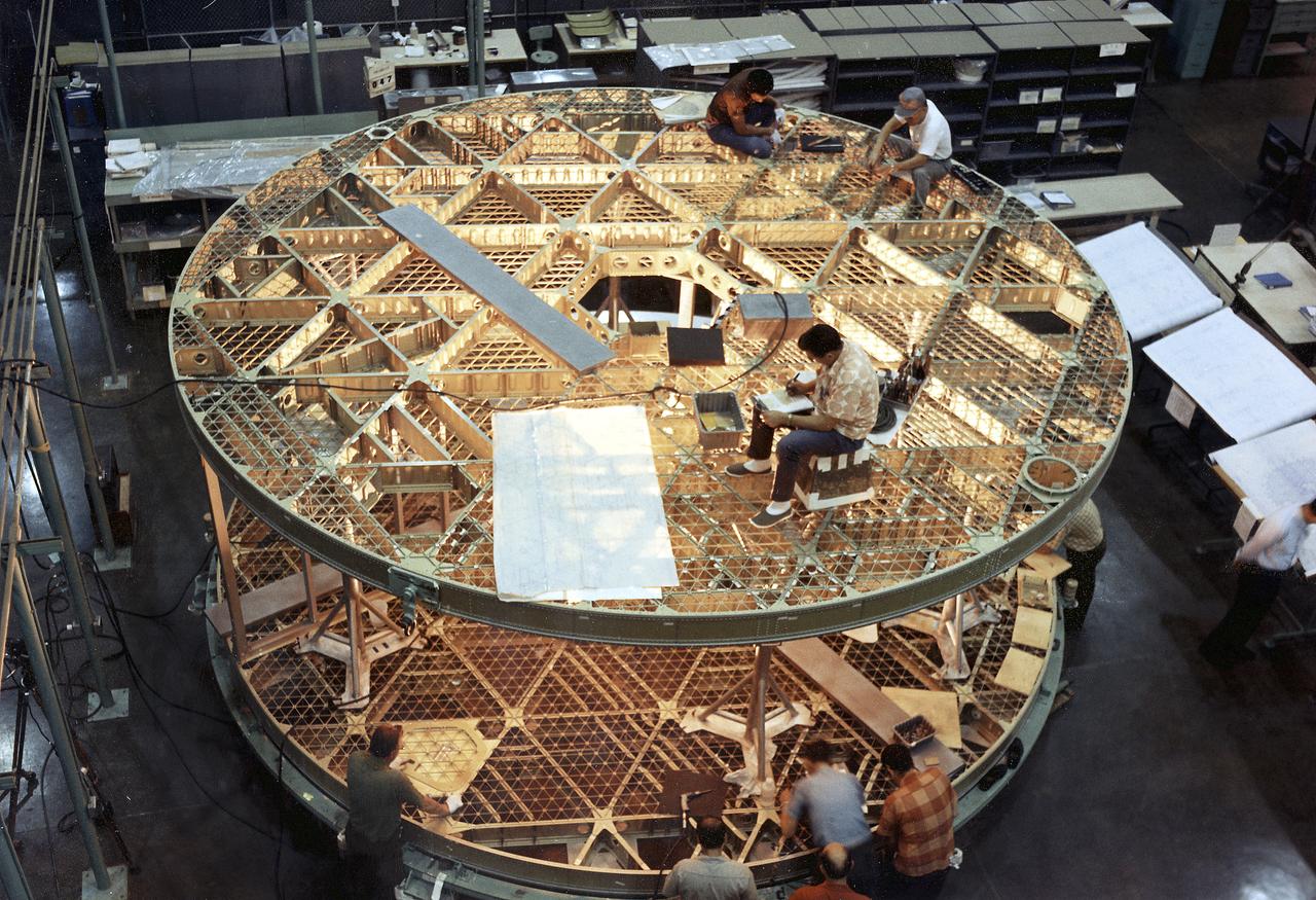 This photograph was taken during assembly of the bottom and upper floors of the Skylab Orbital Workshop (OWS). The OWS was divided into two major compartments. The lower level provided crew accommodations for sleeping, food preparation and consumption, hygiene, waste processing and disposal, and performance of certain experiments. The upper level consisted of a large work area and housed water storage tanks, a food freezer, storage vaults for film, scientific airlocks, mobility and stability experiment equipment, and other experimental equipment. 