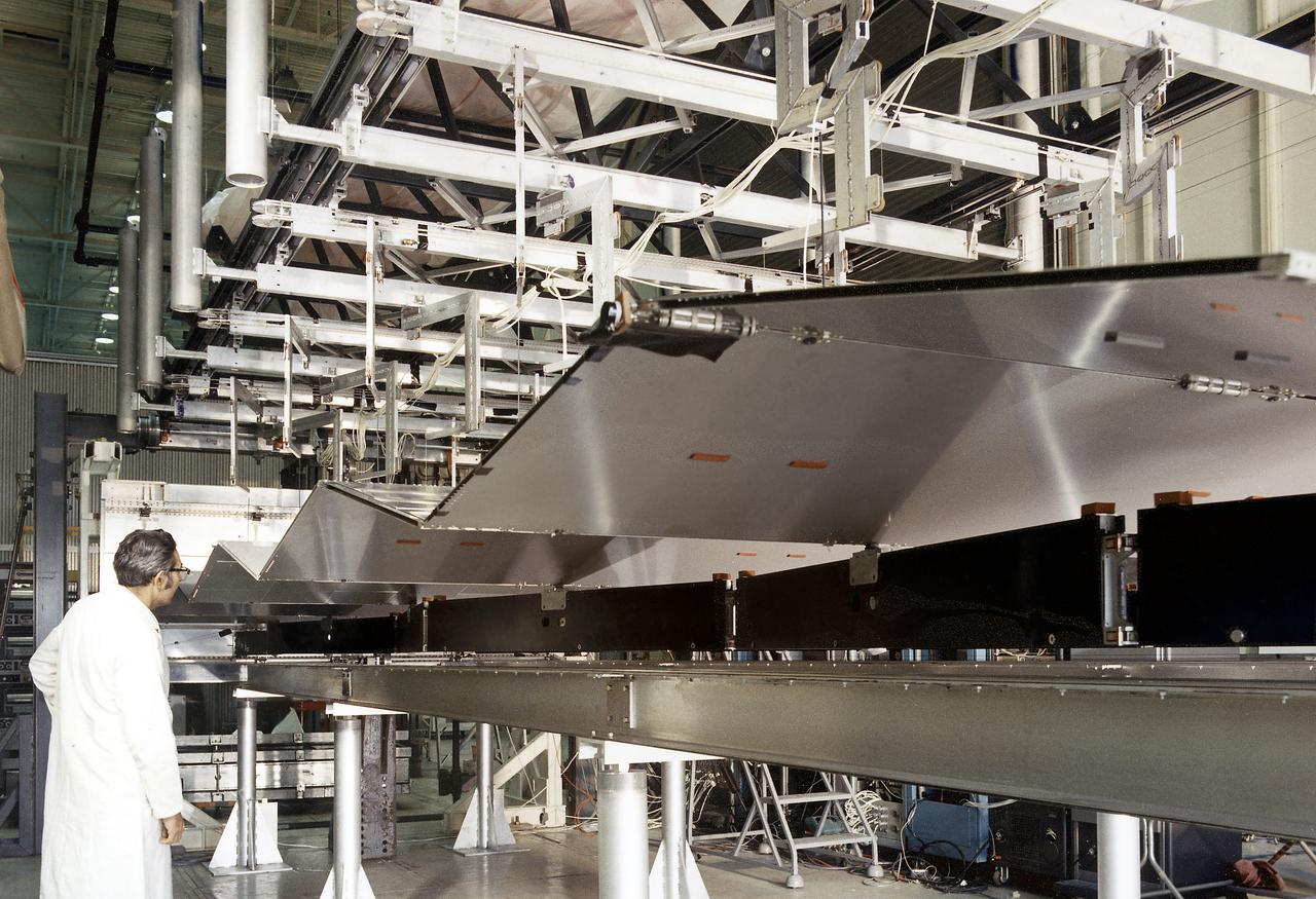 This is a photograph of a technician checking on a solar array wing for the Orbital Workshop as it is deployed. A solar array, consisting of two wings covered on one side with solar cells, was mounted outside the workshop to generate electrical power to augment the power generated by another solar array mounted on the solar observatory. 