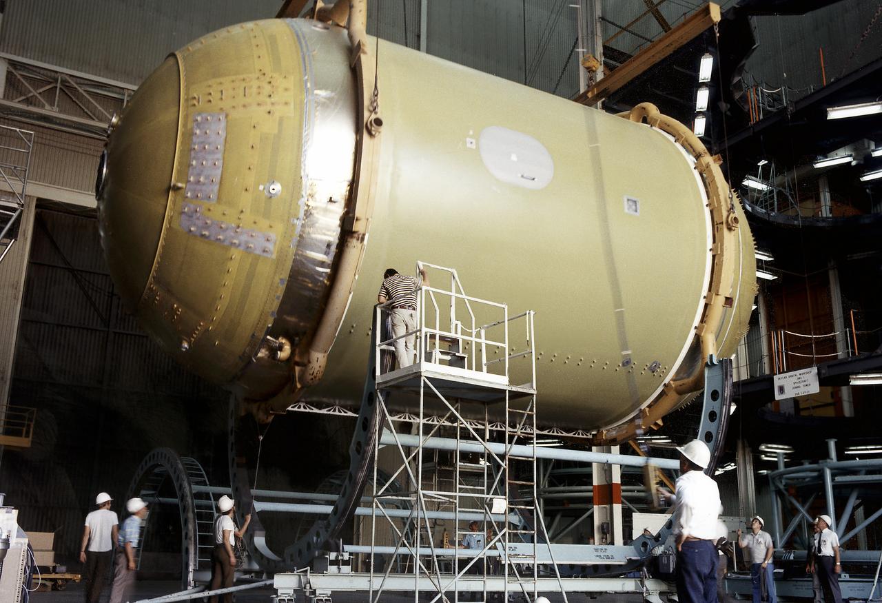 This photographs shows technicians positioning the Skylab Orbital Workshop (OWS) on a rotating work dolly during the assembly phase of the OWS at the McDornell Douglas facility in California. The OWS was the living and working quarters for the astronauts. The Marshall Space Flight Center (MSFC) had responsibility for developing and integrating most of the major components of the Skylab: the Orbital Workshop (OWS), Airlock Module (AM), Multiple Docking Adapter (MDA), Apollo Telescope Mount (ATM), Payload Shroud (PS), and most of the experiments. 