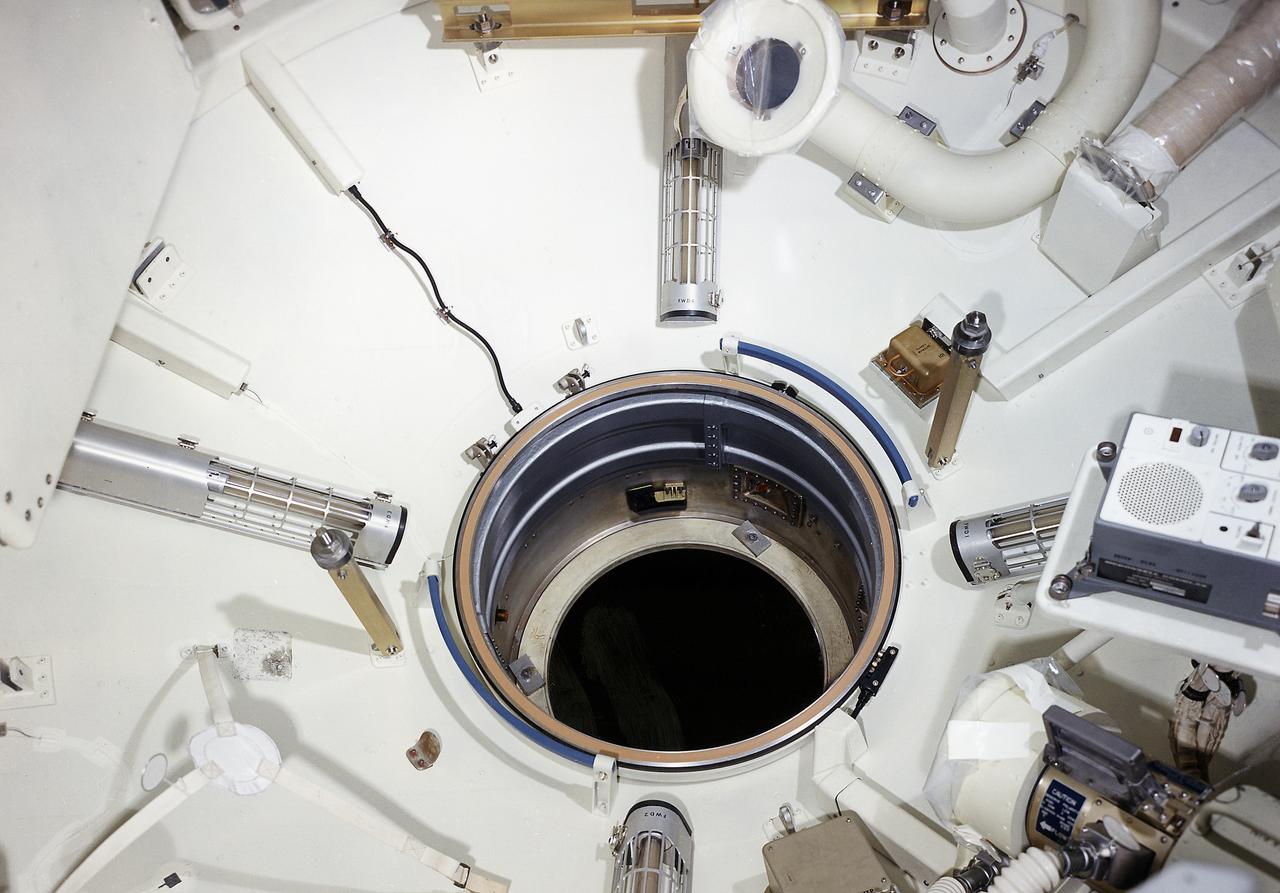 This August 1971 interior photograph of Skylab's Multiple Docking Adapter (MDA) flight article, undergoing outfitting at the Martin-Marietta Corporation's Space Center facility in Denver, Colorado, shows the forward cone area and docking tunnel (center) that attached to the Apollo Command Module. Designed and manufactured by the Marshall Space Flight Center, the MDA housed the control units for the Apollo Telescope Mount, Earth Resources Experiment Package, and Zero-Gravity Materials Processing Facility and provided a docking port for the Apollo Command Module.