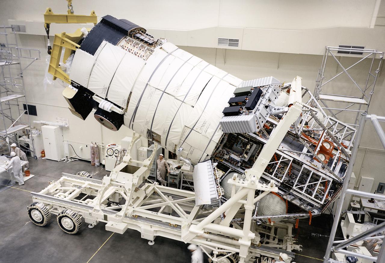 This photograph shows the flight article of the mated Airlock Module (AM) and Multiple Docking Adapter (MDA) being lowering into horizontal position on a transporter. Although the AM and the MDA were separate entities, they were in many respects simply two components of a single module. The AM enabled crew members to conduct extravehicular activities outside Skylab as required for experiment support. Oxygen and nitrogen storage tanks needed for Skylab's life support system were mounted on the external truss work of the AM. Major components in the AM included Skylab's electric power control and distribution station, environmental control system, communication system, and data handling and recording systems. The MDA, forward of the AM, provided docking facilities for the Command and Service Module. It also accommodated several experiment systems, among them the Earth Resource Experiment Package, the materials processing facility, and the control and display console needed for the Apollo Telescope Mount solar astronomy studies. The AM was built by McDornell Douglas and the MDA was built by Martin Marietta. The Marshall Space Flight Center was responsible for the design and development of the Skylab hardware and experiment management. 