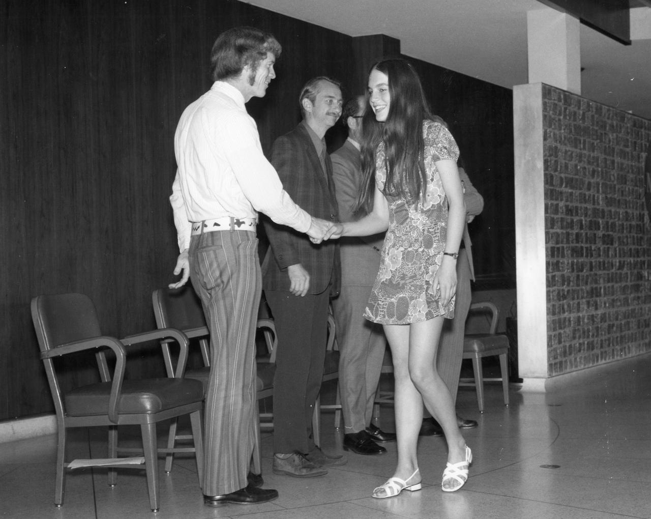 Princeton, New Jersey high school student, Alison Hopfield, is greeted by astronauts Russell L. Schweickart (left) and Owen K. Garriott (center) during a tour of the Marshall Space Flight Center (MSFC). Hopfield was among 25 winners of a contest in which some 3,500 high school students proposed experiments for the following year’s Skylab mission. The nationwide scientific competition was sponsored by the National Science Teachers Association and the National Aeronautics and Space Administration (NASA). The winning students, along with their parents and sponsor teachers, visited MSFC where they met with scientists and engineers, participated in design reviews for their experiments, and toured MSFC facilities. Of the 25 students, 6 did not see their experiments conducted on Skylab because the experiments were not compatible with Skylab hardware and timelines. Of the 19 remaining, 11 experiments required the manufacture of additional equipment. 
