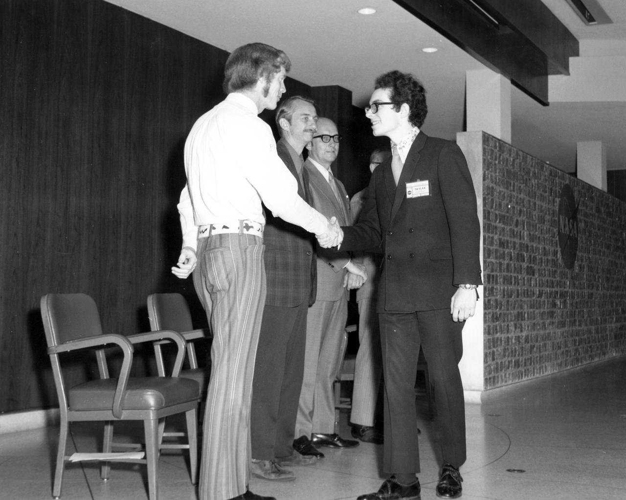 Berkley, Michigan high school student, Kirk M. Sherhart, is greeted by (left to right): Astronauts Russell L. Schweickart, and Owen K. Garriott; Marshall Space Flight Center (MSFC) Skylab Program Manager, Leland Belew; and MSFC Director of Administration and Technical Services, David Newby, during a tour of MSFC. Sherhart was among 25 winners of a contest in which some 3,500 high school students proposed experiments for the following year’s Skylab mission. The nationwide scientific competition was sponsored by the National Science Teachers Association and the National Aeronautics and Space Administration (NASA). The winning students, along with their parents and sponsor teachers, visited MSFC where they met with scientists and engineers, participated in design reviews for their experiments, and toured MSFC facilities. Of the 25 students, 6 did not see their experiments conducted on Skylab because the experiments were not compatible with Skylab hardware and timelines. Of the 19 remaining, 11 experiments required the manufacture of additional equipment. 