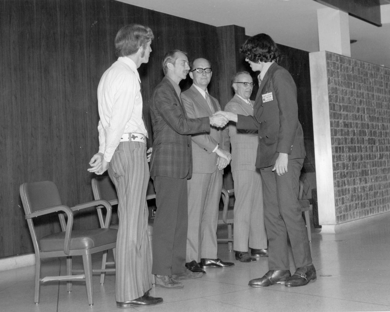 North Rochester, New York high school student, Robert L. Staehle, is greeted by (left to right): Astronauts Russell L. Schweickart, and Owen K. Garriott; Marshall Space Flight Center (MSFC) Skylab Program Manager, Leland Belew; and MSFC Director of Administration and Technical Services, David Newby, during a tour of MSFC. Staehle was among 25 winners of a contest in which some 3,500 high school students proposed experiments for the following year’s Skylab mission. The nationwide scientific competition was sponsored by the National Science Teachers Association and the National Aeronautics and Space Administration (NASA). The winning students, along with their parents and sponsor teachers, visited MSFC where they met with scientists and engineers, participated in design reviews for their experiments, and toured MSFC facilities. Of the 25 students, 6 did not see their experiments conducted on Skylab because the experiments were not compatible with Skylab hardware and timelines. Of the 19 remaining, 11 experiments required the manufacture of additional equipment. 