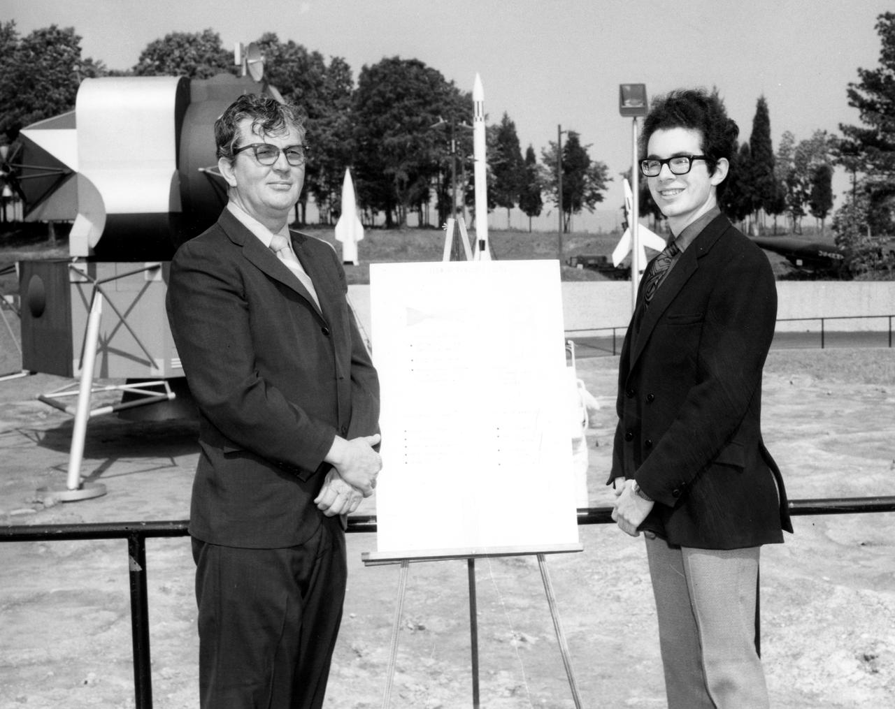 Kirk M. Sherhart, high school student from Berkley, Michigan, discussed a his proposed Skylab experiment with Dr. Robert Head of the Marshall Space Flight Center (MSFC) during his visit to the center. The lunar surface scene in the background is one of many space exhibits at the Alabama Space and Rocket Center in nearby Huntsville, Alabama. Sherhart was among 25 winners of a contest in which some 3,500 high school students proposed experiments for the following year’s Skylab mission. The nationwide scientific competition was sponsored by the National Science Teachers Association and the National Aeronautics and Space Administration (NASA). The winning students, along with their parents and sponsor teachers, visited MSFC where they met with scientists and engineers, participated in design reviews for their experiments, and toured MSFC facilities. Of the 25 students, 6 did not see their experiments conducted on Skylab because the experiments were not compatible with Skylab hardware and timelines. Of the 19 remaining, 11 experiments required the manufacture of additional equipment. 