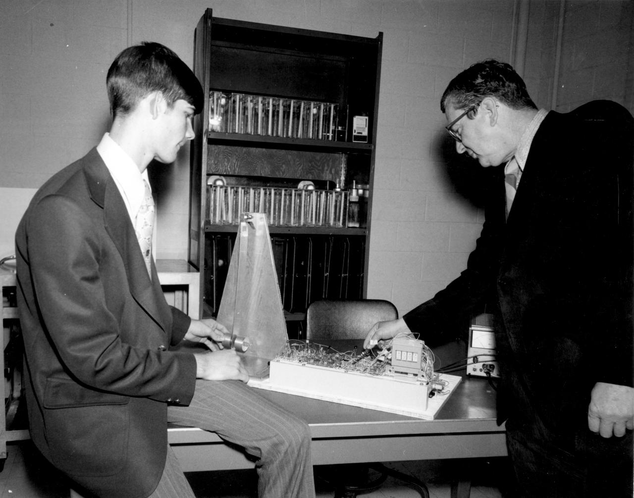 Rockford, Illinois high school student, Vincent Converse (left), and Robert Head of the Marshall Space Flight Center (MSFC), check out the equipment to be used in conducting the student’s experiment aboard the Skylab the following year. His experiment, “Zero Gravity Mass Measurement” used a simple leaf spring with the mass to be weighed attached to the end.  An electronic package oscillated the spring at a specific rate and the results were recorded electronically. Converse was among 25 winners of a contest in which some 3,500 high school students proposed experiments for the following year’s Skylab mission. The nationwide scientific competition was sponsored by the National Science Teachers Association and the National Aeronautics and Space Administration (NASA). The winning students, along with their parents and sponsor teachers, visited MSFC two months earlier where they met with scientists and engineers, participated in design reviews for their experiments, and toured MSFC facilities. Of the 25 students, 6 did not see their experiments conducted on Skylab because the experiments were not compatible with Skylab hardware and timelines. Of the 19 remaining, 11 experiments required the manufacture of additional equipment. 
