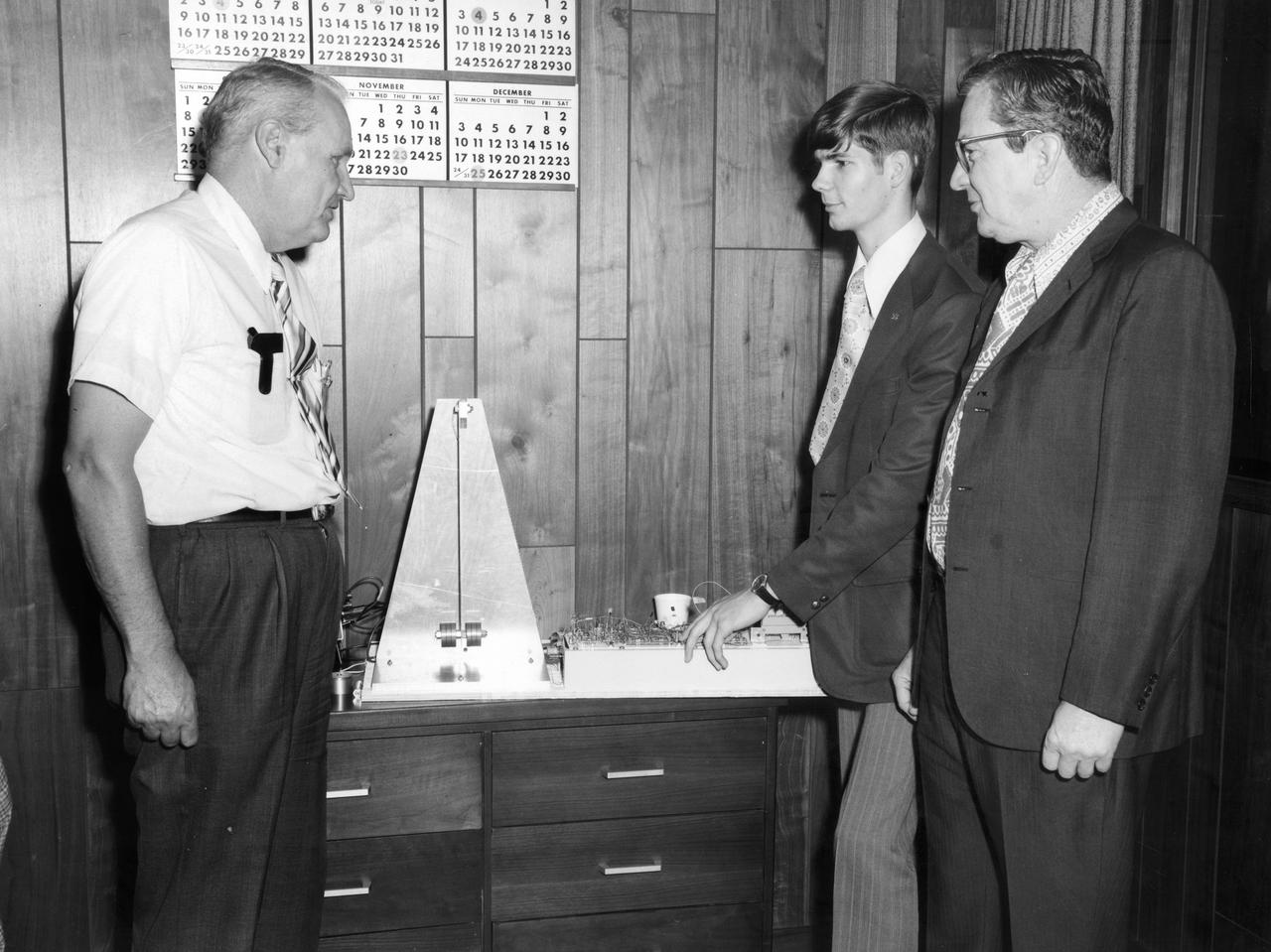 Rockford, Illinois high school student, Vincent Converse, discussed his proposed Skylab experiment with Dr. Robert Head (right) and Gene Greshman of Marshall Space Flight Center (MSFC). His experiment, “Zero Gravity Mass Measurement” used a simple leaf spring with the mass to be weighed attached to the end.  The electronic package oscillated the spring at a specific rate and the results were recorded electronically.  Converse was among 25 winners of a contest in which some 3,500 high school students proposed experiments for the following year’s Skylab mission. Of the 25 students, 6 did not see their experiments conducted on Skylab because the experiments were not compatible with Skylab hardware and timelines. Of the 19 remaining, 11 experiments required the manufacture of equipment, such as that of Converse’s experiment.