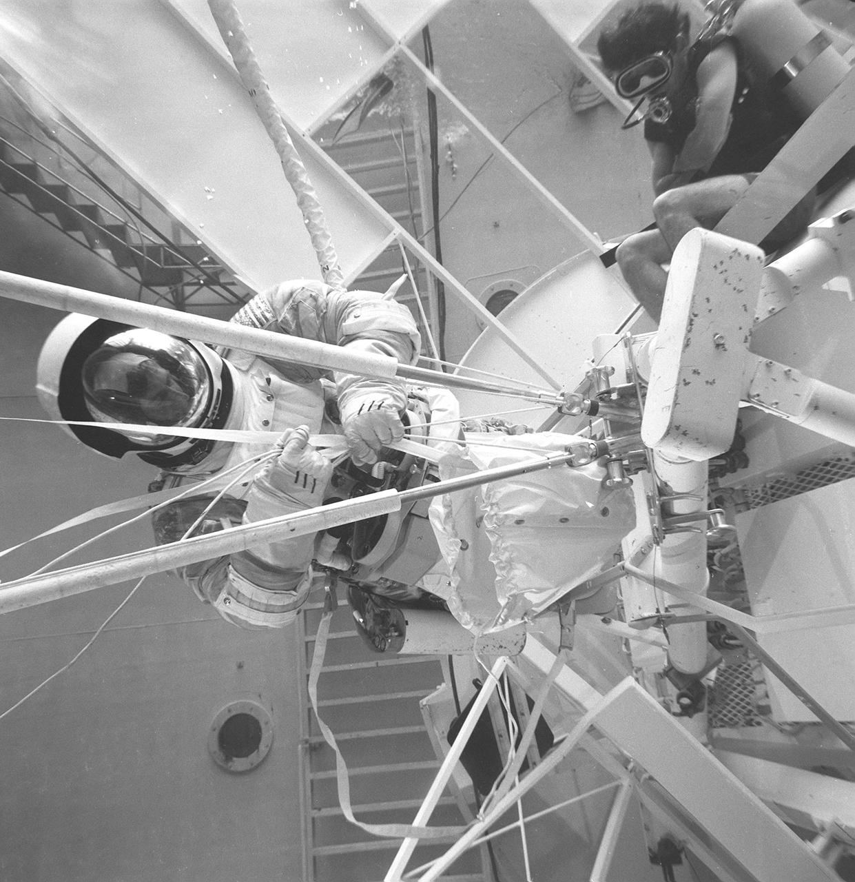 This photograph was taken in the Marshall Space Flight Center (MSFC) Neutral Buoyancy Simulator (NBS) during the testing of an emergency procedure to deploy a twin-pole sunshade to protect the orbiting workshop from overheating due to the loss of its thermal shield. The spacecraft suffered damage to its sunshield during its launch on May 14, 1973. This photograph shows the base plate used to hold the twin-pole in place, the bag to hold the fabric sail, and the lines that were used to draw the sail into place. Extensive testing and many hours of practice in simulators, such as the NBS, helped prepare the Skylab crewmen for extravehicular performance in the weightless environment. This huge water tank simulated the weightless environment that the astronauts would encounter in space.