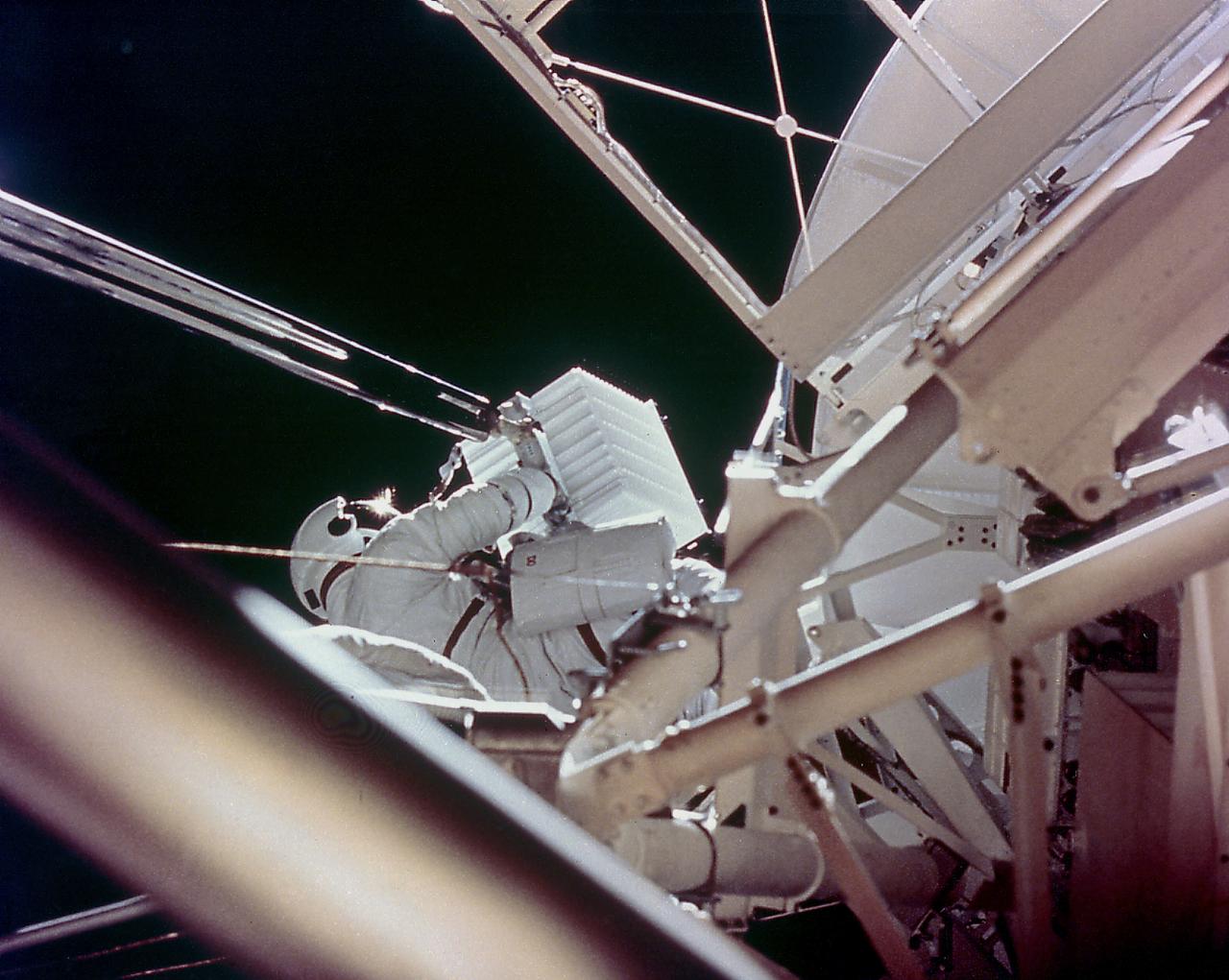This onboard photograph depicts Astronaut Owen Garriott atop the Apollo Telescope Mount, removing a film magazine (white box) from one of Skylab's solar telescopes during an Extravehicular Activity (EVA) in the second marned Skylab mission (Skylab-3). A long boom transported it back into the waiting hands of another crew member at the airlock door below. During the operation, Garriott, film, boom, and Skylab were 435 kilometers high and speeding around the Earth at 29,000 kilometers per/hour. Because they moved together with no wind resistance, there was little sense of motion. 
