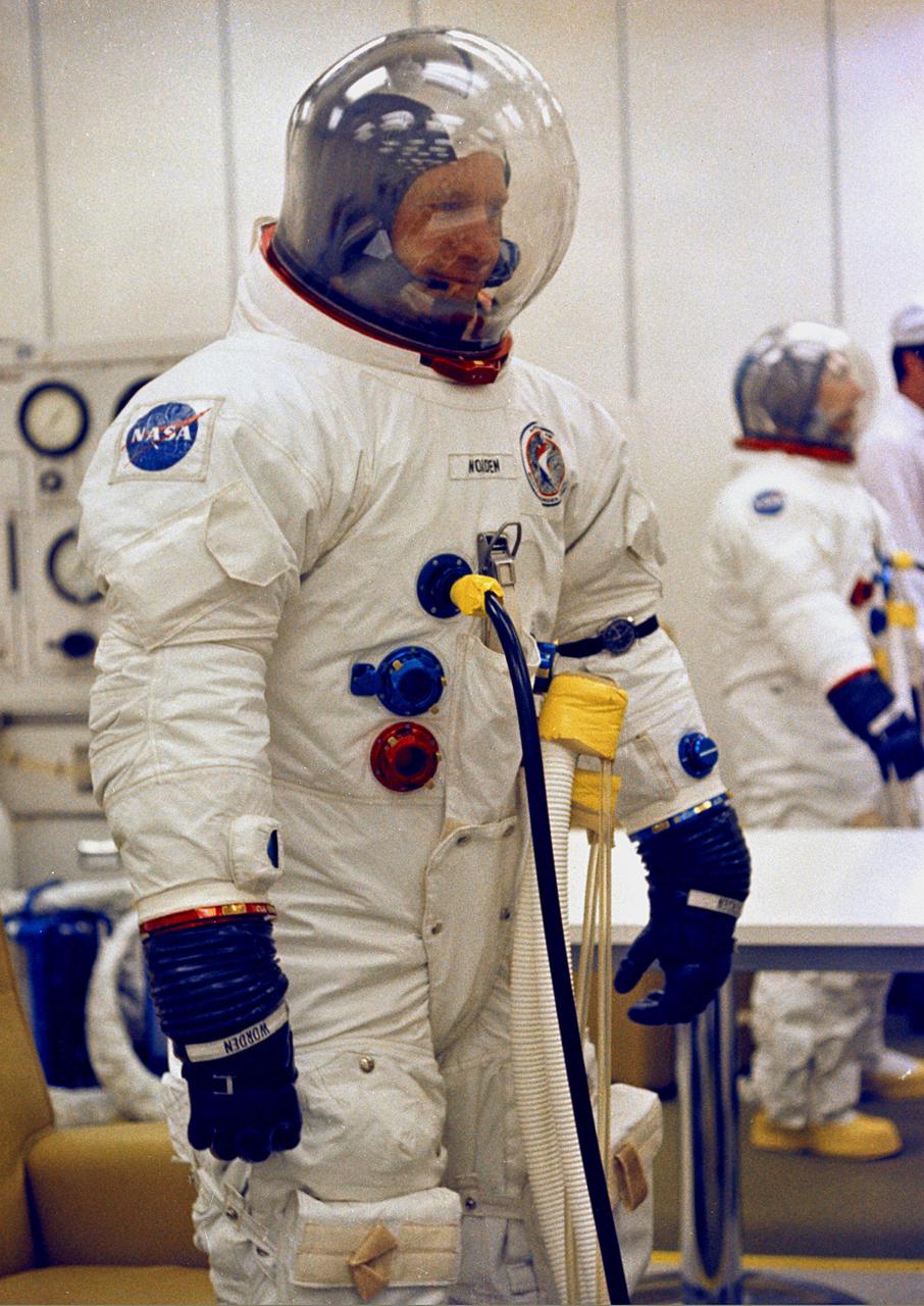 KENNEDY SPACE CENTER, FLA. - Apollo 15 Command Module Pilot Alfred M. Worden undergoes spacesuit pressure checks prior to participating in the space vehicle Countdown Demonstration Test. Lunar Module Pilot James B. Irwin is visible in the rear while David R. Scott, the Commander for Apollo 15, is not shown. The test is a rehearsal in preparation for the scheduled Moon mission, scheduled no earlier than July 26, 1971.