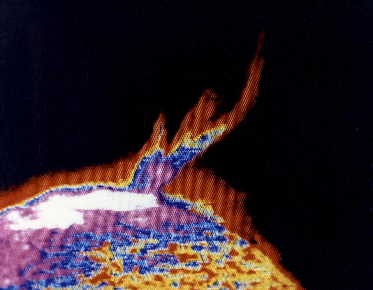 This photograph shows a solar prominence in action, one of Skylab's many splendorous views. It was taken on August 21, 1973. Interpretation of the rich store of Skylab ultraviolet solar data was facilitated by computerized color enhancement of the original black-and-white images, highlighting subtle but important brightness differences. 