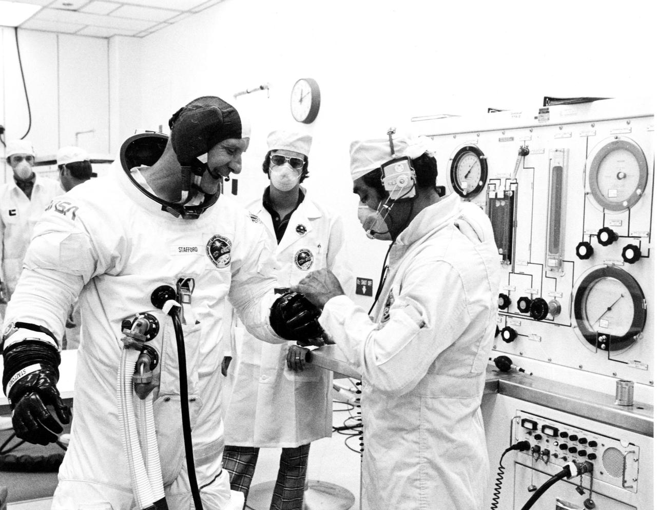 KENNEDY SPACE CENTER, FLA. -- A suit technician helps ASTP astronaut Thomas Stafford don his pressure suit.  After suitup, Stafford and crewmen Vance Brand and Donald Slayton walked to the transfer van for the trip to the launch pad.