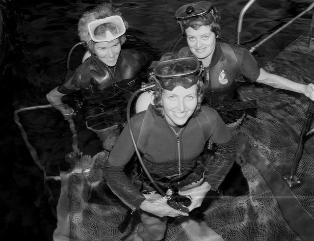 Candid shots of Carolyn Griner (front), Drs. Mary-Helen Johnston and Ann Whitaker (L to R) wearing scuba gear at the Neutral Buoyancy Simulator (NBS) for training.