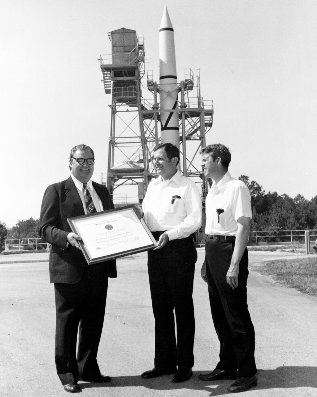 On October 02, 1976, Marshall Space Flight Center’s (MSFC) Redstone test stand was received into the National Registry of Historical Places.  Photographed in front of the Redstone test stand are Dr. William R. Lucas, MSFC Center Director from June 15, 1974 until July 3, 1986, as he is accepting a certificate of registration from Madison County Commission Chairman James Record, and Huntsville architect Harvie Jones.  