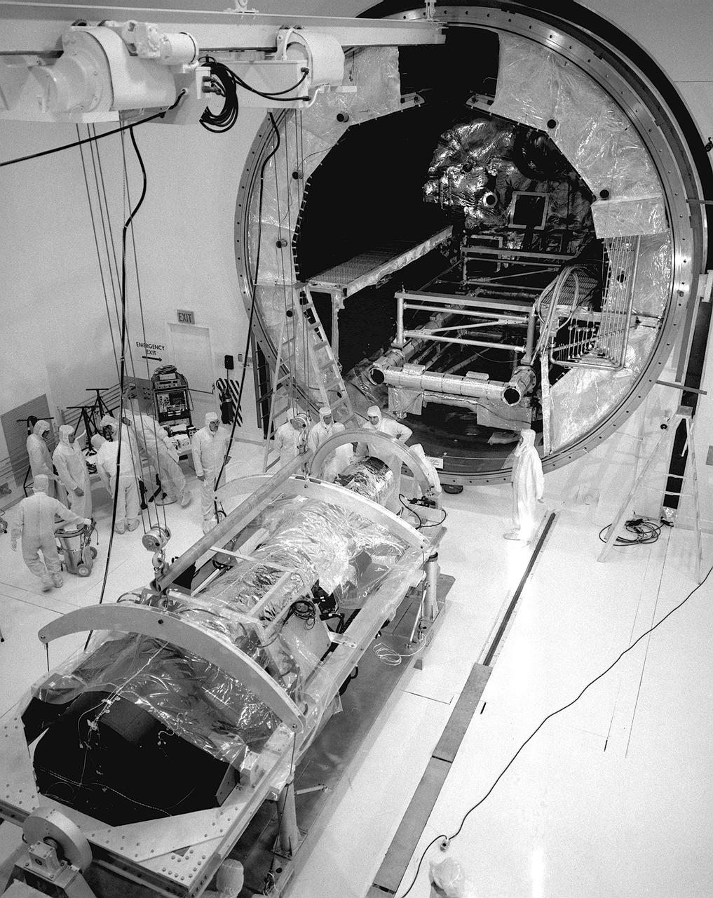 This photograph is of the High Energy Astronomy Observatory (HEAO)-2 telescope being evaluated by engineers in the clean room of the X-Ray Calibration Facility at the Marshall Space Flight Center (MSFC). The MSFC was heavily engaged in the technical and scientific aspects, testing and calibration, of the HEAO-2 telescope The HEAO-2 was the first imaging and largest x-ray telescope built to date. The X-Ray Calibration Facility was built in 1976 for testing MSFC's HEAO-2. The facility is the world's largest, most advanced laboratory for simulating x-ray emissions from distant celestial objects. It produced a space-like environment in which components related to x-ray telescope imaging are tested and the quality of their performance in space is predicted. The original facility contained a 1,000-foot long by 3-foot diameter vacuum tube (for the x-ray path) cornecting an x-ray generator and an instrument test chamber. Recently, the facility was upgraded to evaluate the optical elements of NASA's Hubble Space Telescope, Chandra X-Ray Observatory and Compton Gamma-Ray Observatory. 