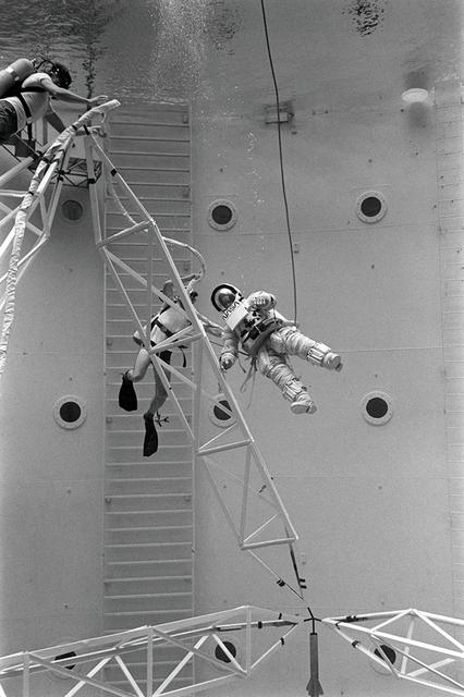 Once the United States' space program had progressed from Earth's orbit into outerspace, the prospect of building and maintaining a permanent presence in space was realized. To accomplish this feat, NASA launched a temporary workstation, Skylab, to discover the effects of low gravity and weightlessness on the human body, and also to develop tools and equipment that would be needed in the future to build and maintain a more permanent space station. The structures, techniques, and work schedules had to be carefully designed to fit this unique construction site. The components had to be lightweight for transport into orbit, yet durable. The station also had to be made with removable parts for easy servicing and repairs by astronauts. All of the tools necessary for service and repairs had to be designed for easy manipulation by a suited astronaut. And construction methods had to be efficient due to limited time the astronauts could remain outside their controlled environment. In lieu of all the specific needs for this project, an environment on Earth had to be developed that could simulate a low gravity atmosphere. A Neutral Buoyancy Simulator (NBS) was constructed by NASA Marshall Space Flight Center (MSFC) in 1968. Since then, NASA scientists have used this facility to understand how humans work best in low gravity and also provide information about the different kinds of structures that can be built. With the help of the NBS, building a space station became more of a reality. In a joint venture between NASA/Langley Research Center in Hampton, VA and MSFC, the Assembly Concept for Construction of Erectable Space Structures (ACCESS) was developed and demonstrated at MSFC's NBS. The primary objective of this experiment was to test the ACCESS structural assembly concept for suitability as the framework for larger space structures and to identify ways to improve the productivity of space construction. Pictured is a demonstration of ACCESS.