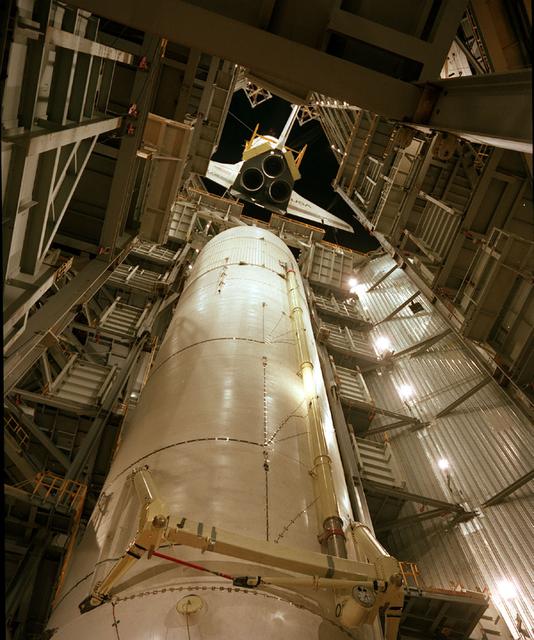 This is an interior ground level view of the Shuttle Orbiter Enterprise being lowered for mating to External Tank (ET) inside Marshall Space Flight Center's Dynamic Test Stand for Mated Vertical Ground Vibration tests (MVGVT). The tests marked the first time ever that the entire shuttle complement (including Orbiter, external tank, and solid rocket boosters) were mated vertically.