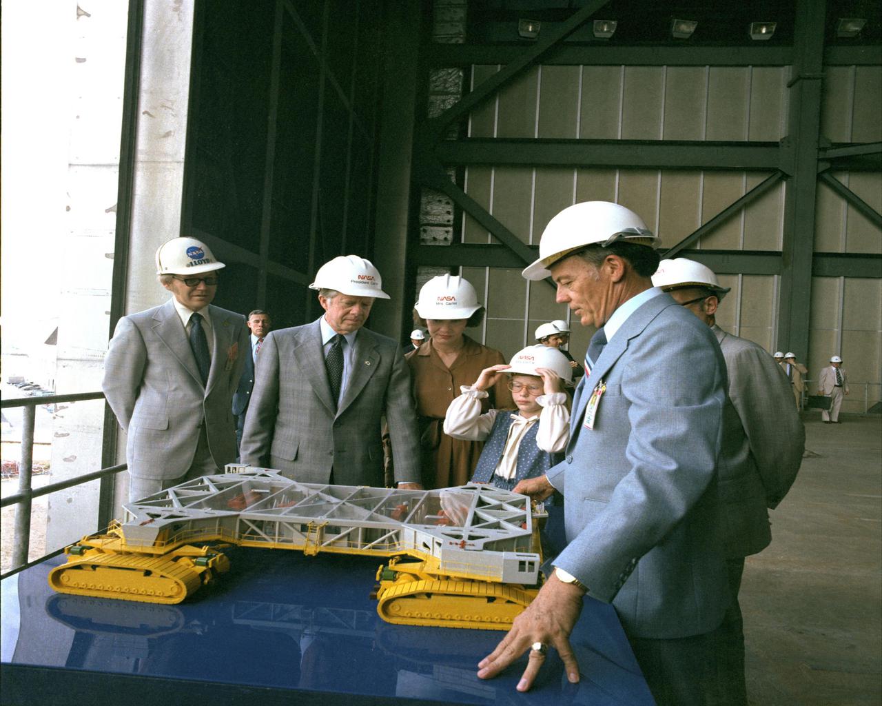 KENNEDY SPACE CENTER, FLA. -- President Jimmy Carter, with wife Rosalynn and daughter Amy, listen to Center Director Lee R. Scherer explain a model of the crawler transporter during their tour of the Kennedy Space Center.